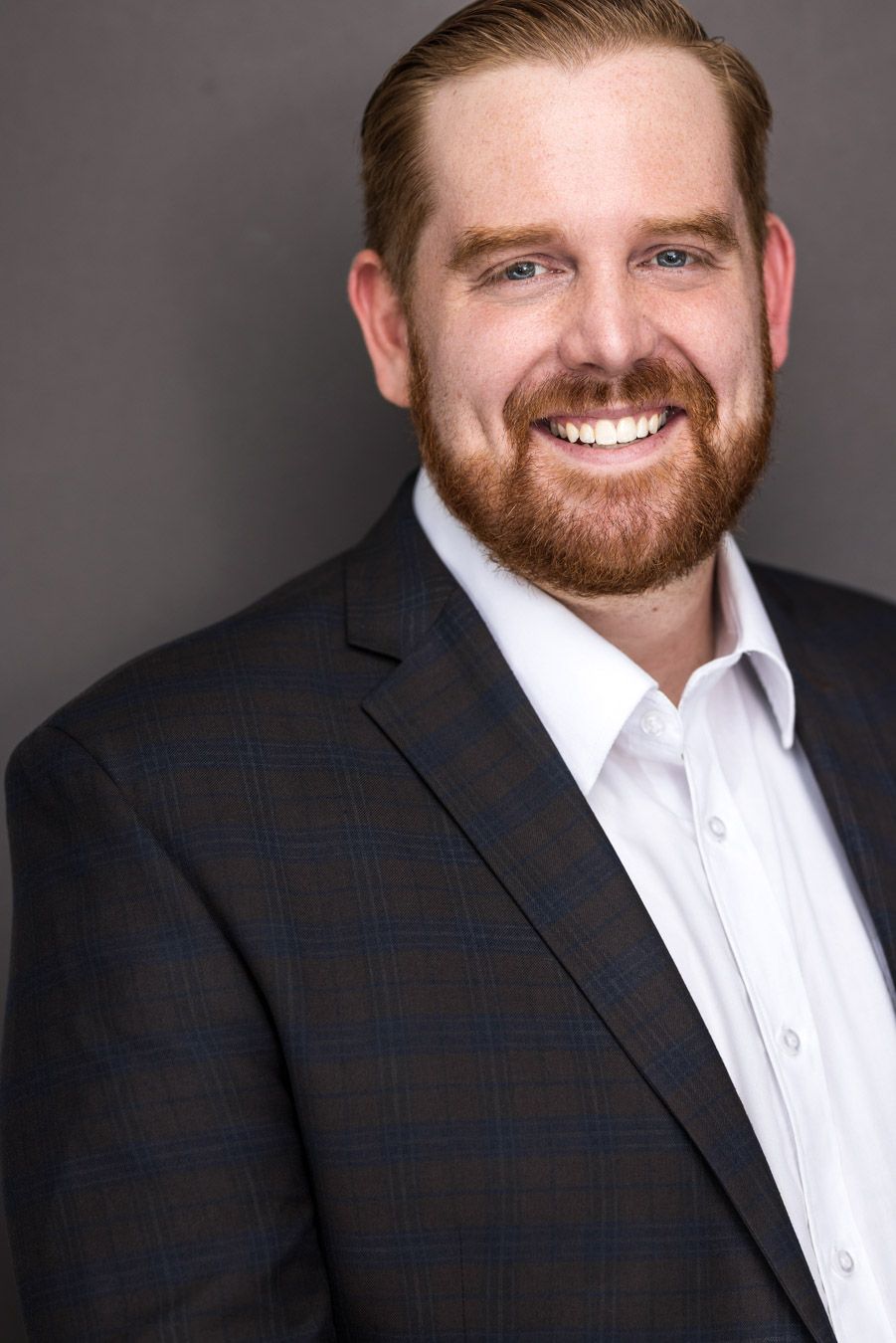 Headshot of a man with a red beard and slicked-back hair, wearing a dark plaid blazer in Hudson Valley Photography Studio.