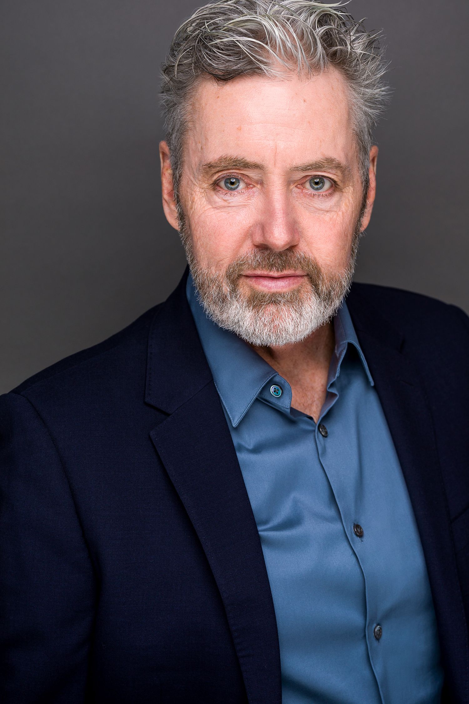 Corporate headshot of a man in a black top against a warm brown backdrop in Beacon, New York