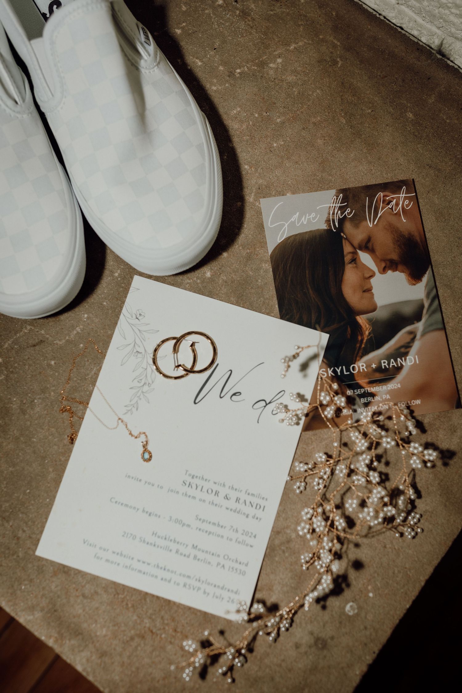 Wedding invitation and save the date card with gold rings, white checkered slip-on shoes, and delicate pearl hair accessories.
