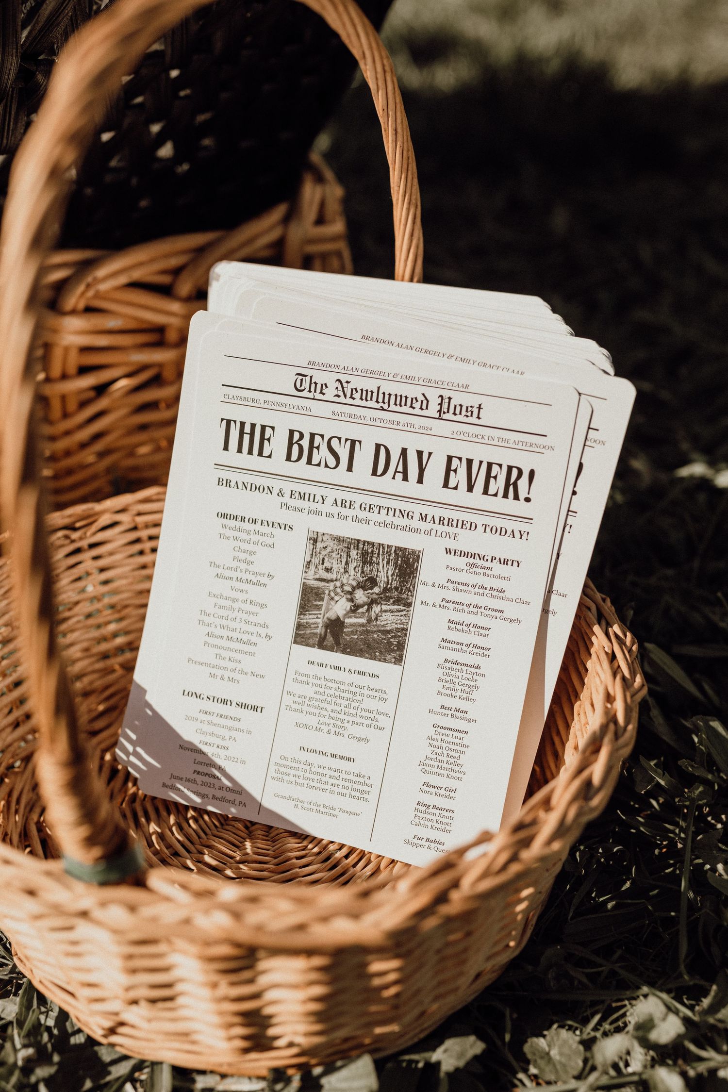 Basket of wedding programs styled as a newspaper headlined The Best Day Ever, announcing Brandon and Emily's wedding.