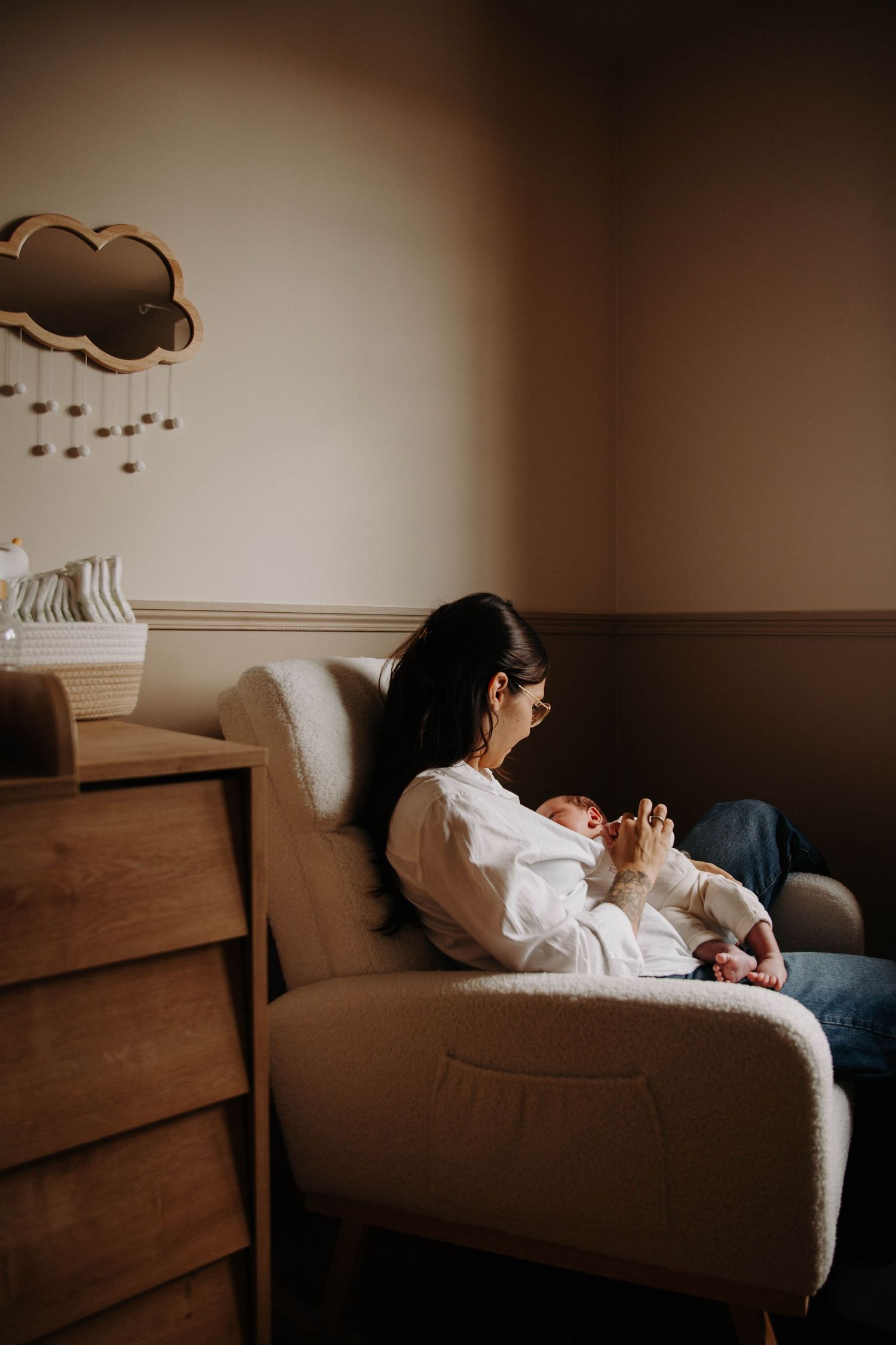 femme et son bébé assis dans un fauteuil dans la chambre de bébé