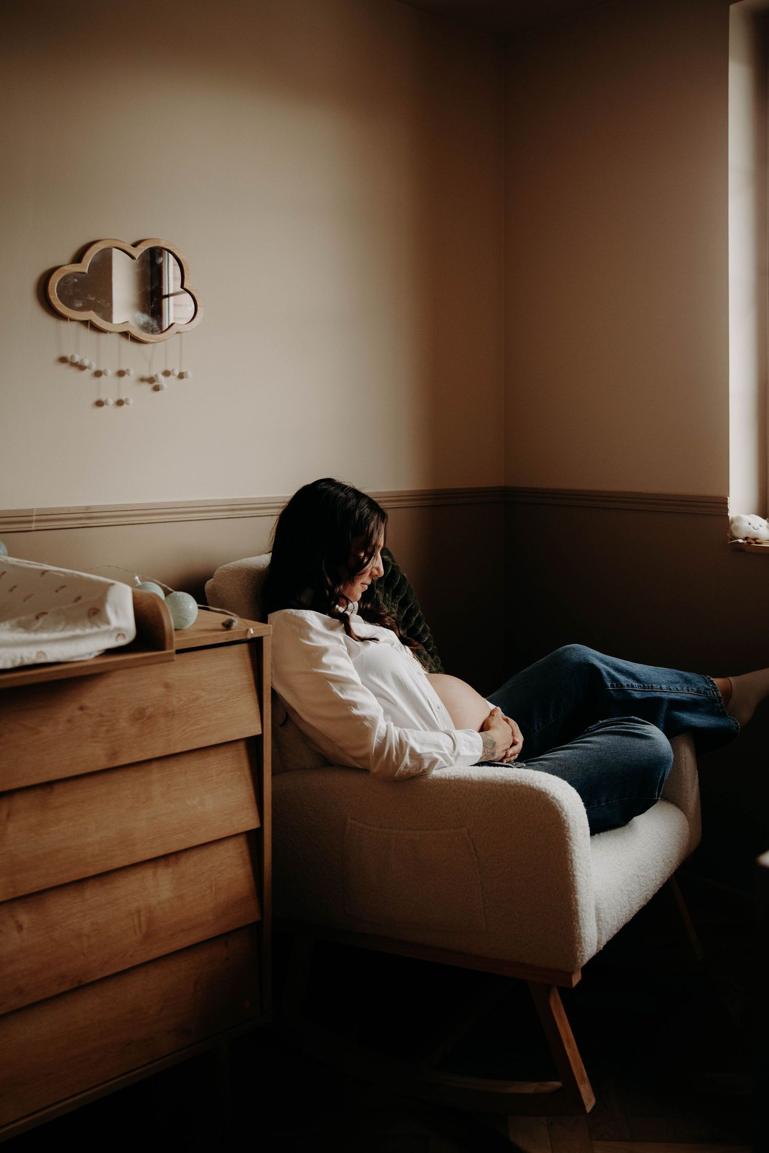 femme enceinte dans un fauteuil dans la futur chambre de leur enfant