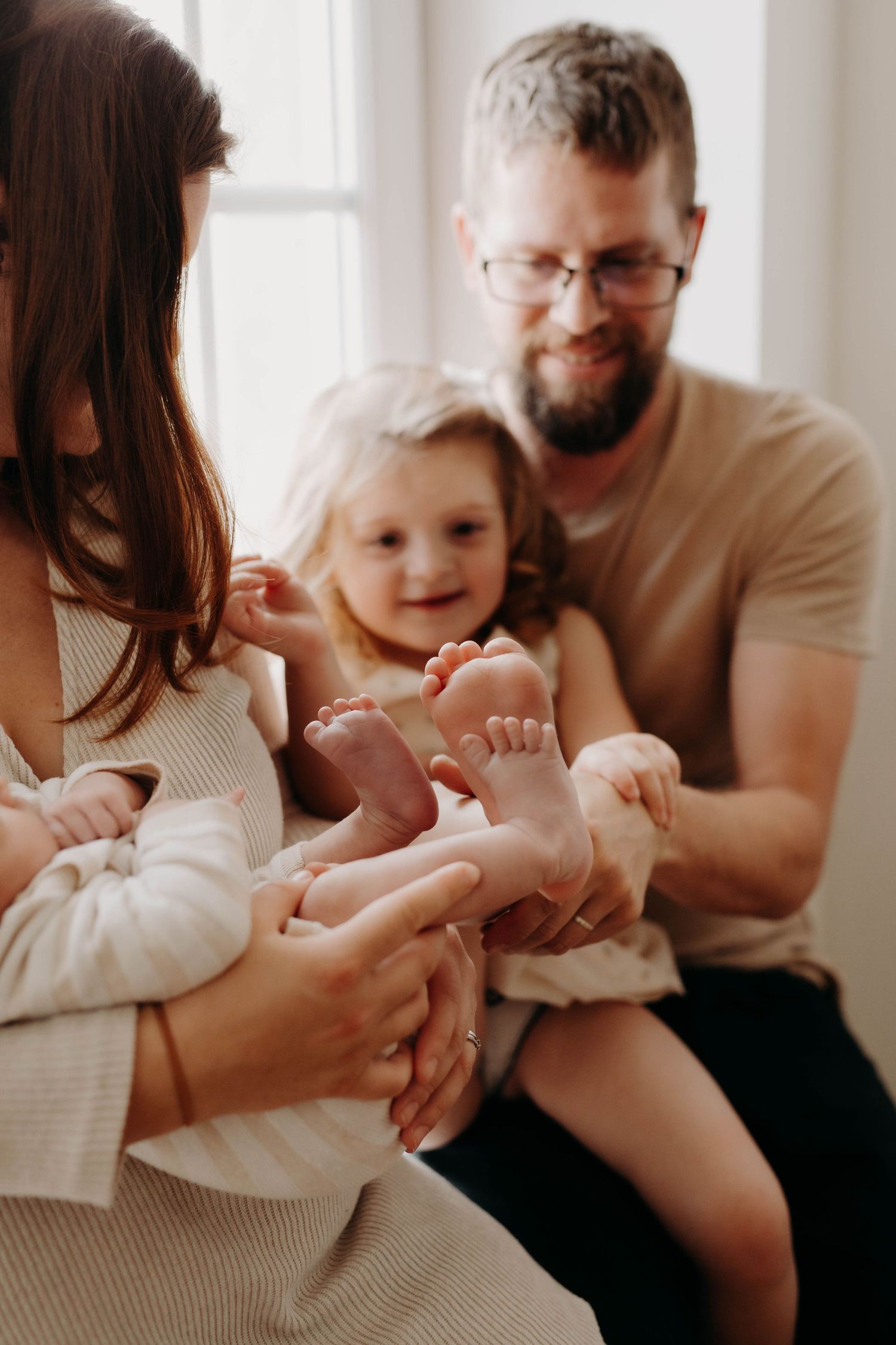 photo de famille ou la petite fille compare la taille de ses pieds avec celle de son petit frère qui vient de naitre
