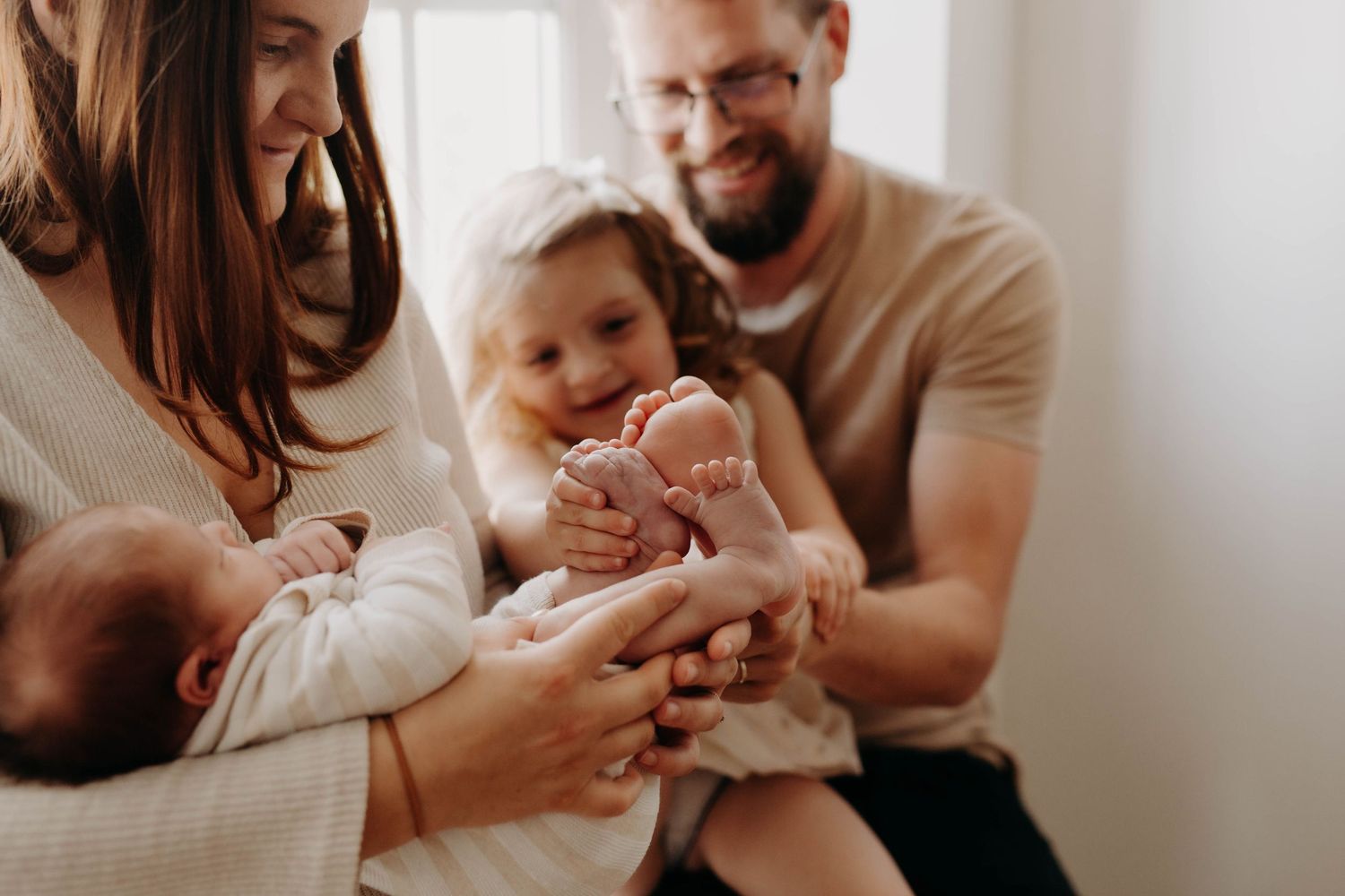 photo de famille ou la petite fille compare la taille de ses pieds avec celle de son petit frère qui vient de naitre