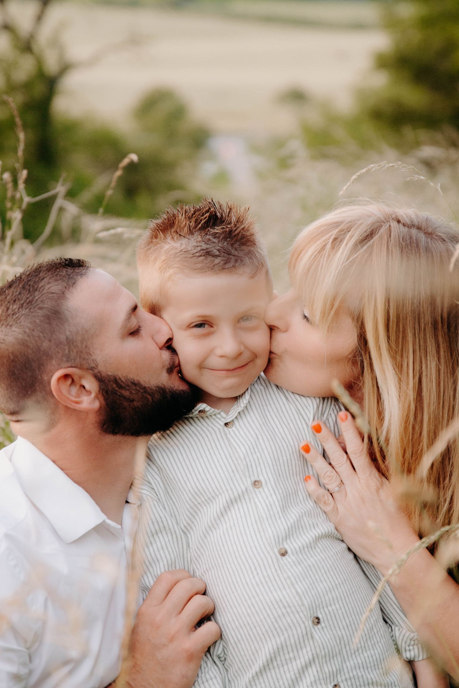 deux parents qui embrassent sur la joue leur fils