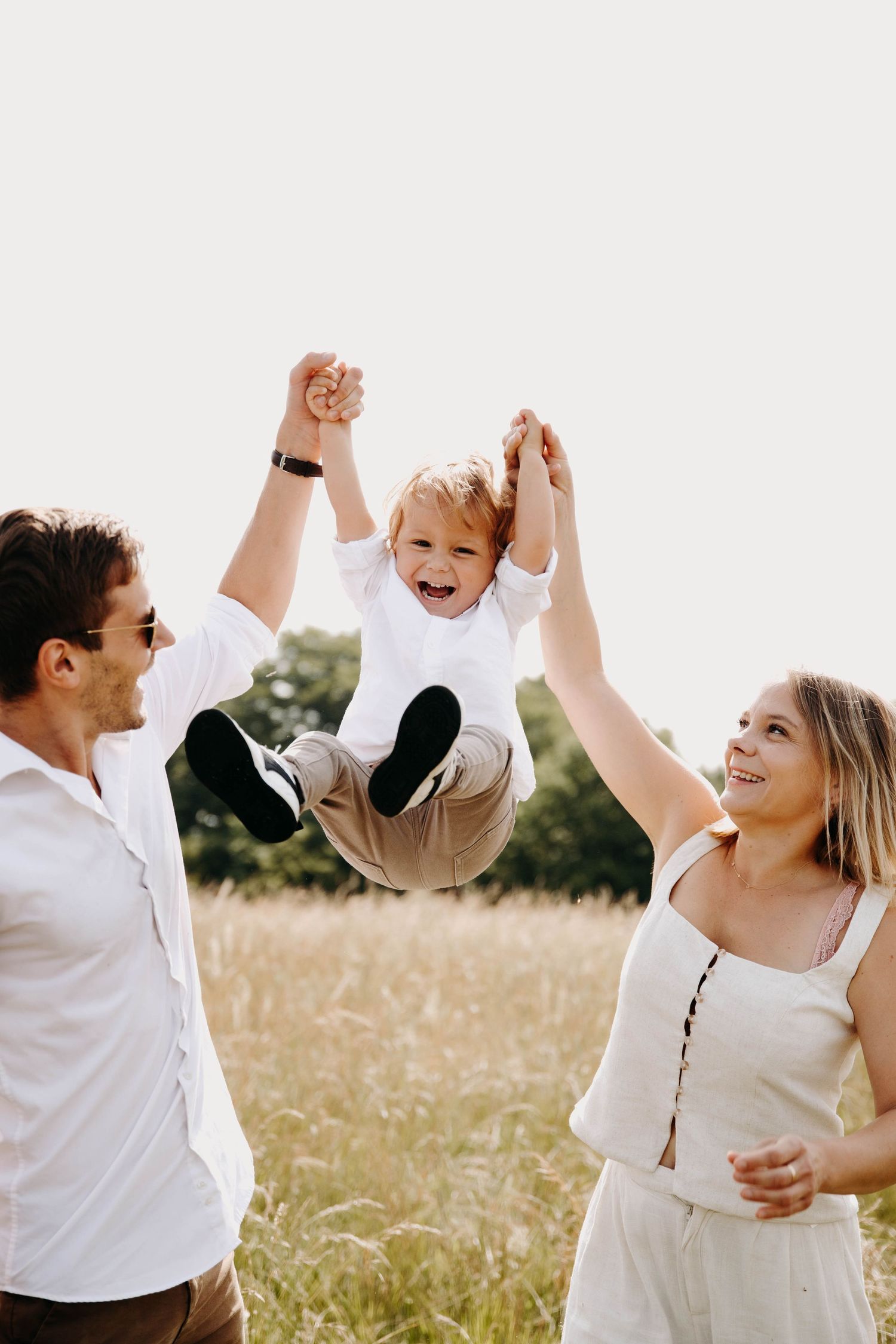 des parents et leur fils qui jouent, le petit garçon est dans les airs, tout sourire