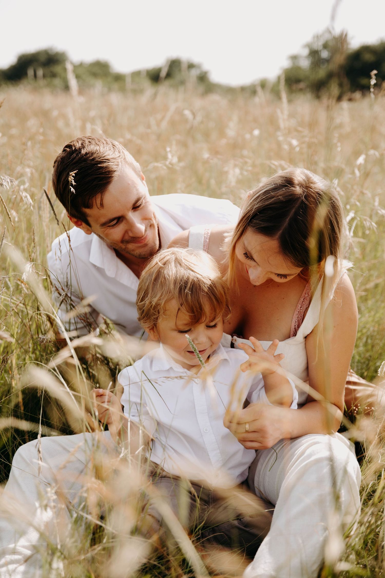 un papa une maman et son fils qui jouent, dans l'herbe