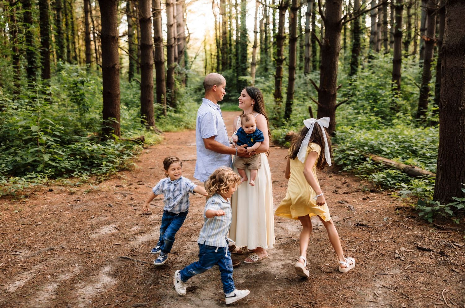 Family photoshoot running through woods with photographer located throughout the Kansas City Metro area. Based in Blue Springs, Missouri.