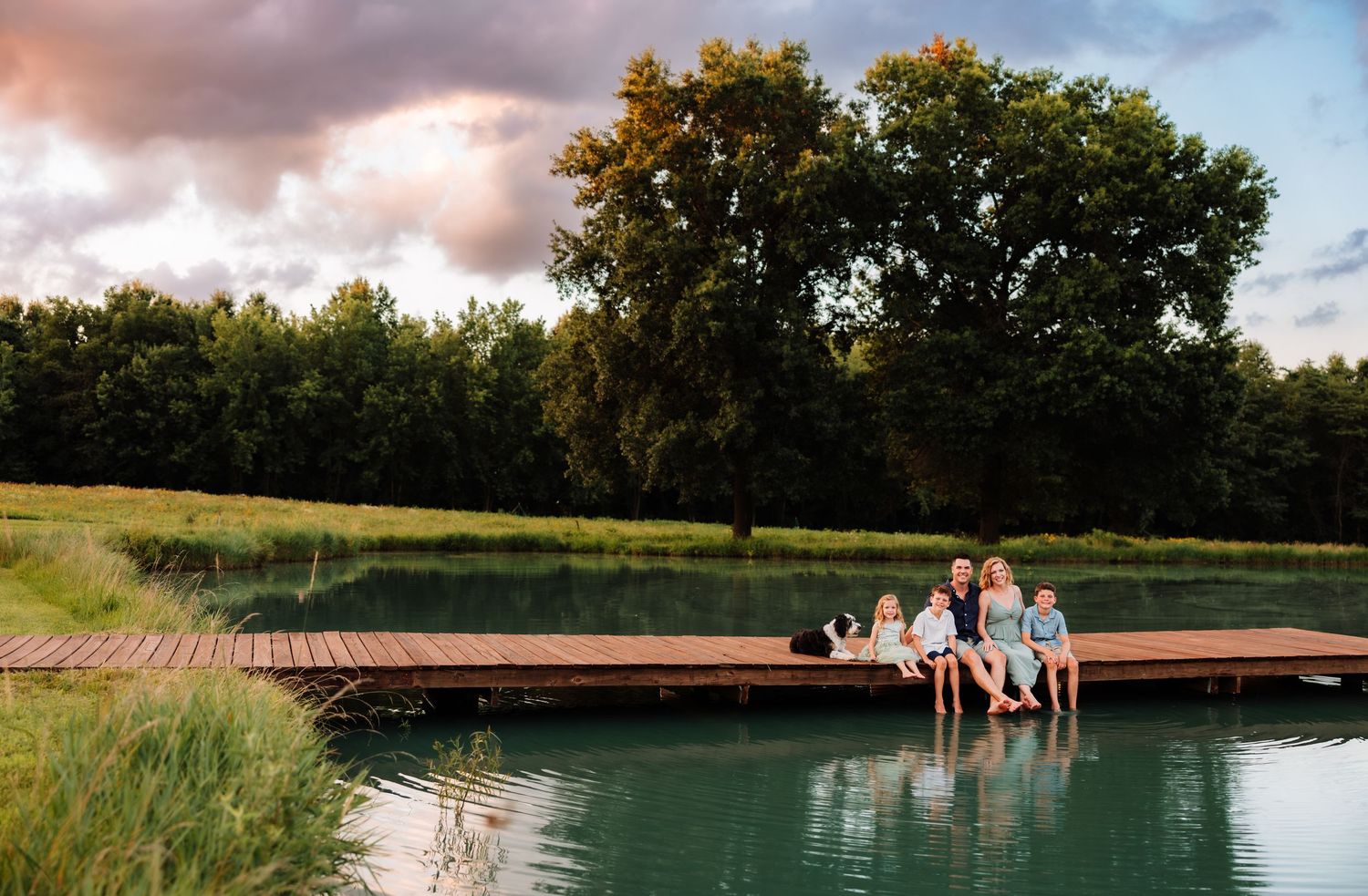 Family photoshoot sitting on a dock with photographer located throughout the Kansas City Metro area. Based in Blue Springs, Missouri.