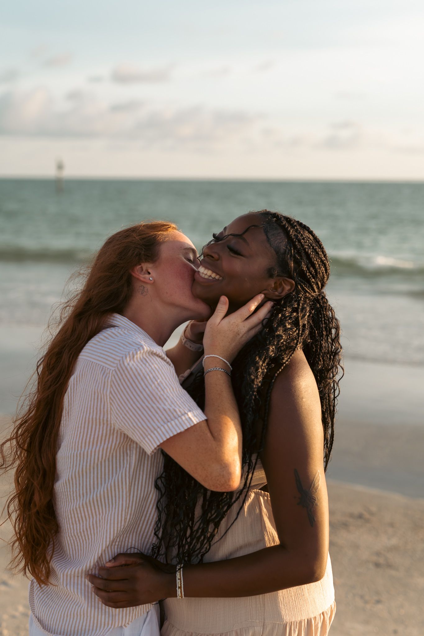 A couple holding sharing a kiss on St. Pete Beach during a golden hour sunset photography session.