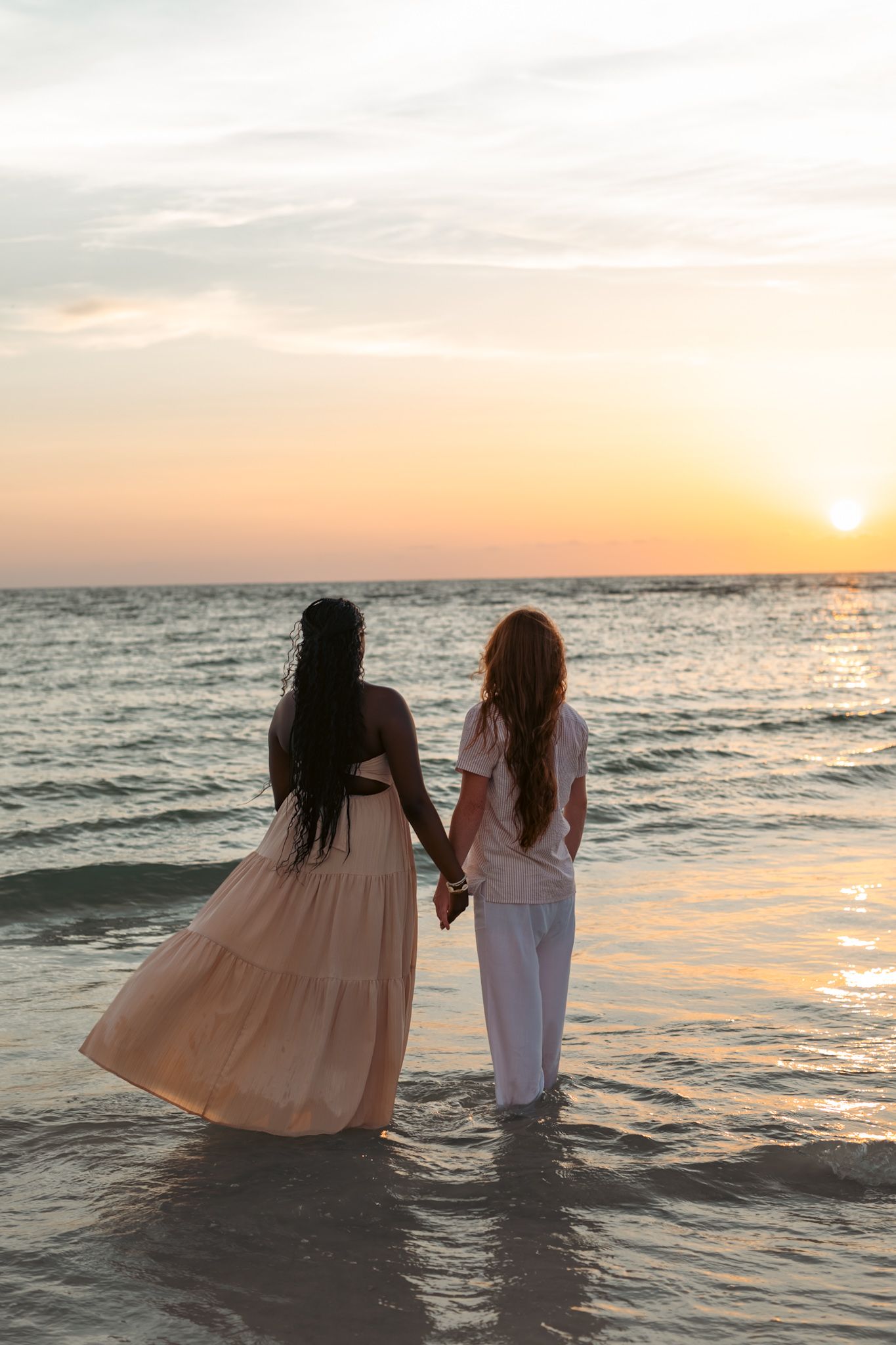 A couple holding hands and walking along St. Pete Beach during a golden hour sunset photography session.