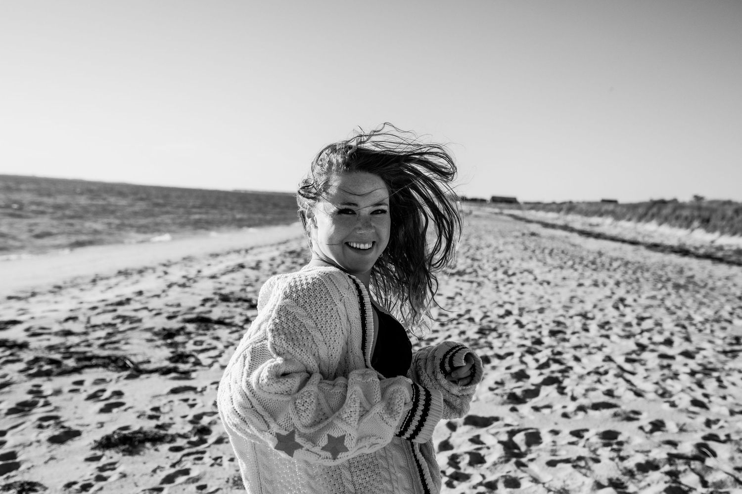 Joyful woman laughing on sandy beach with wind blowing her hair in black and white photo Cape cod beach Boudoir photos