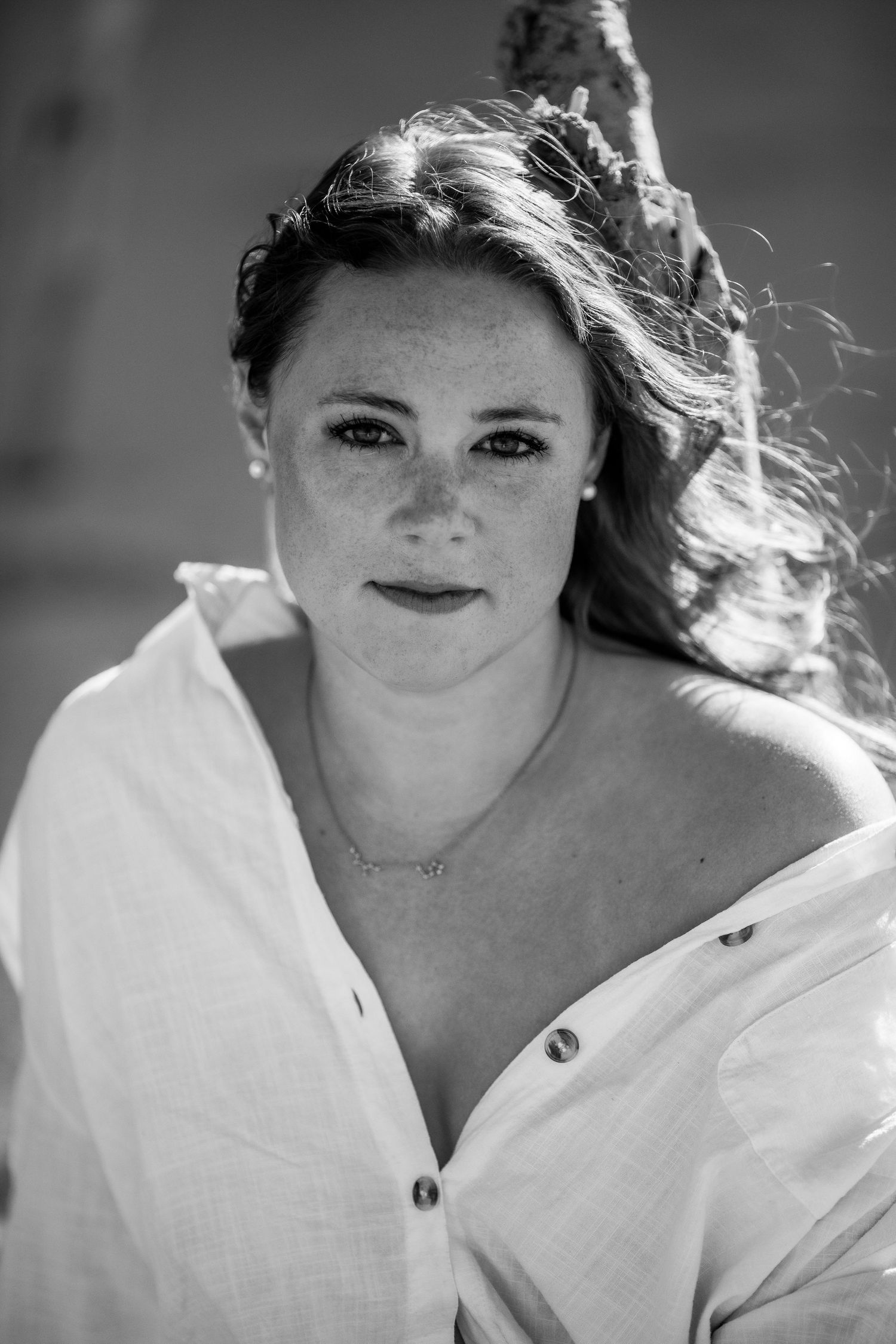 Black and white portrait of a freckled woman with flowing hair in an open white shirt outdoors Cape cod beach Boudoir photos
