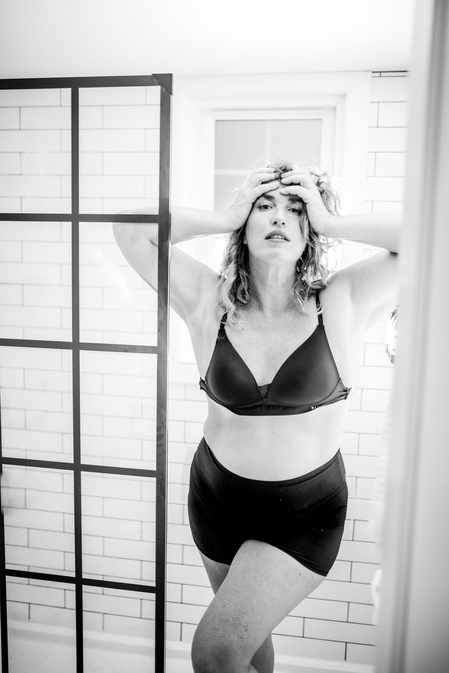 Black and white photo of a woman in lingerie posing in a modern bathroom with subway tiles Cape cod studio Boudoir photos