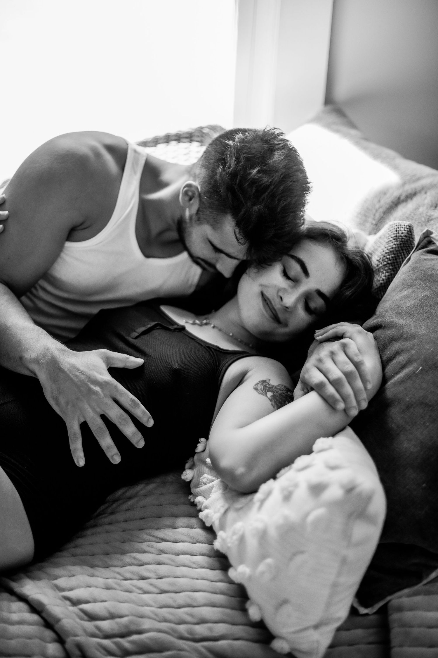 Black and white romantic couple cuddling together on a cozy bed by a bright window Cape cod couples studio Boudoir photos