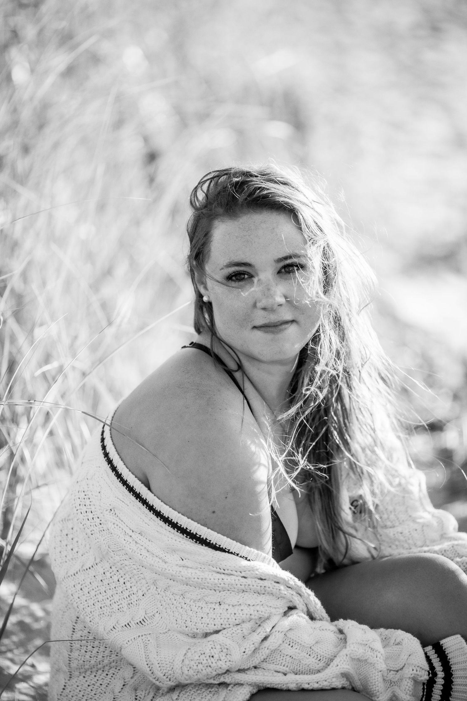 Black and white portrait of a smiling freckled blonde woman sitting among tall beach grasses Cape cod beach Boudoir photos
