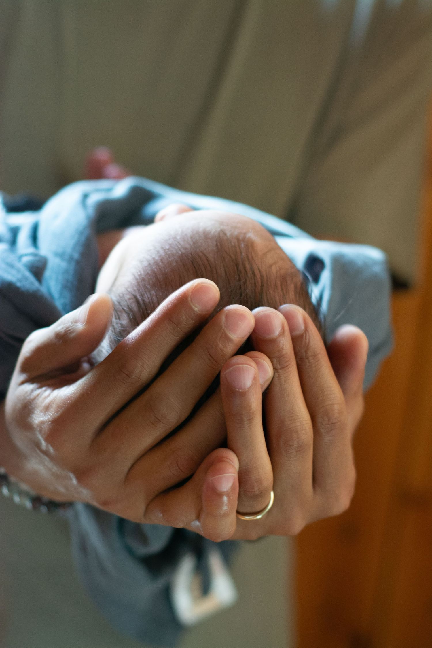 Dads hands wrapped around newborn head, holding him gently newborn photo session
