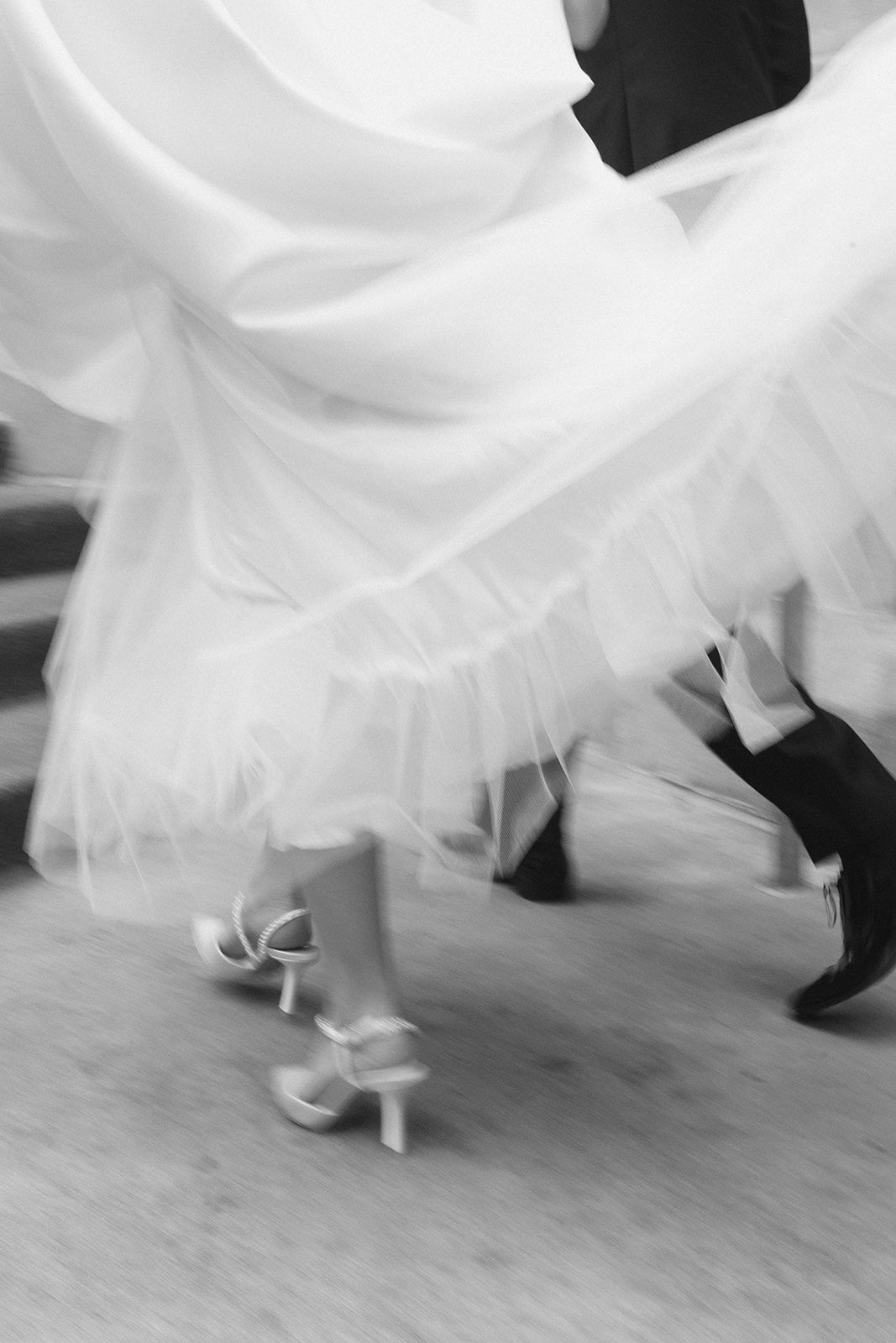 Black and white motion blur photo of bride and groom dancing, showcasing flowing wedding dress.
