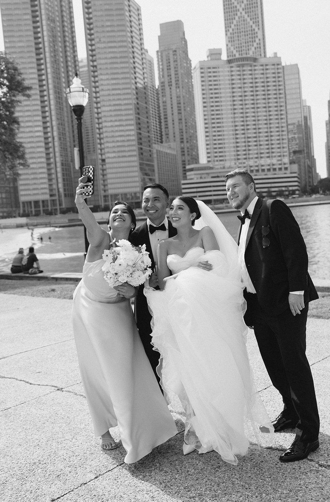 Wedding party takes a fun selfie with Chicago skyline backdrop in black and white photo.