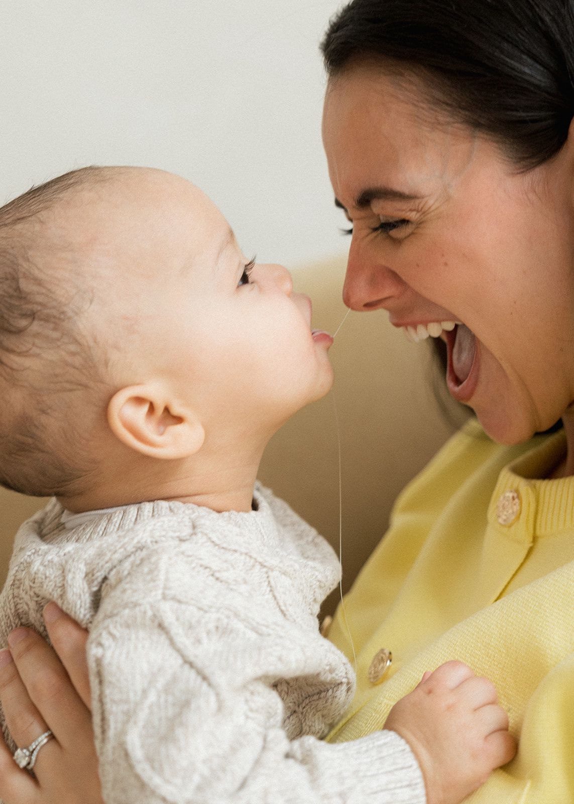 Smiling mother holding her baby close, sharing a joyful nose-to-nose moment together.