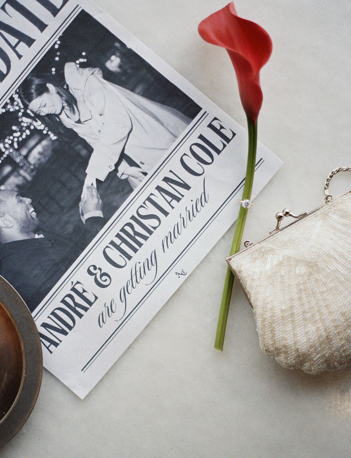 Wedding announcement newspaper featuring Andre and Christian Cole with a red calla lily and pearl clutch purse.