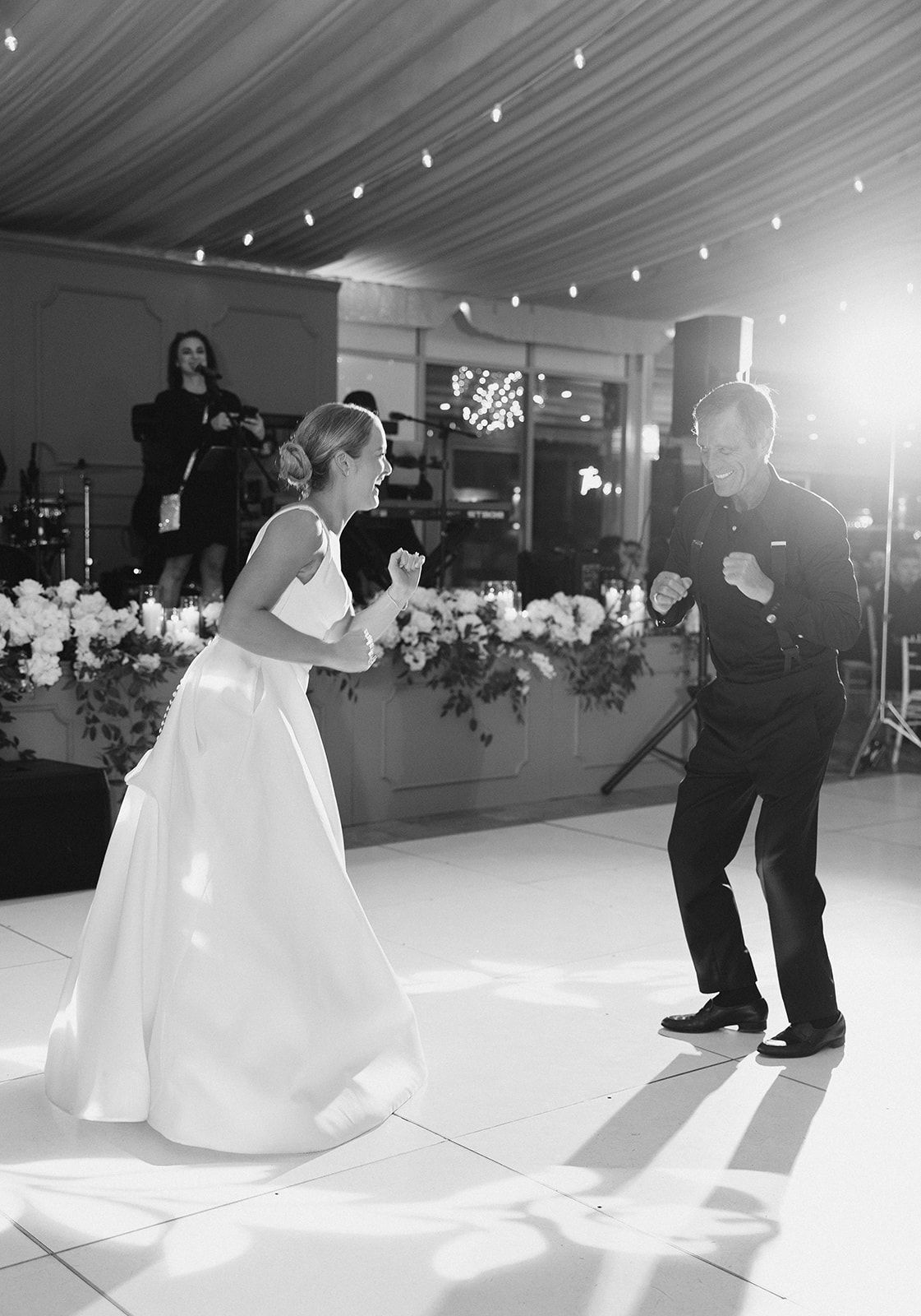 Black and white photo of bride and groom sharing energetic first dance at elegant reception.