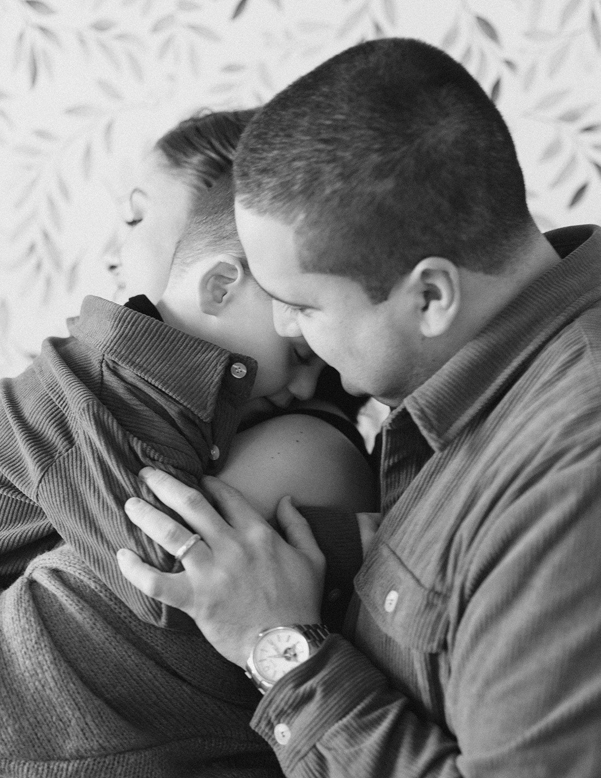 A black and white photo of a man and woman sharing a tender moment with a young child between them.