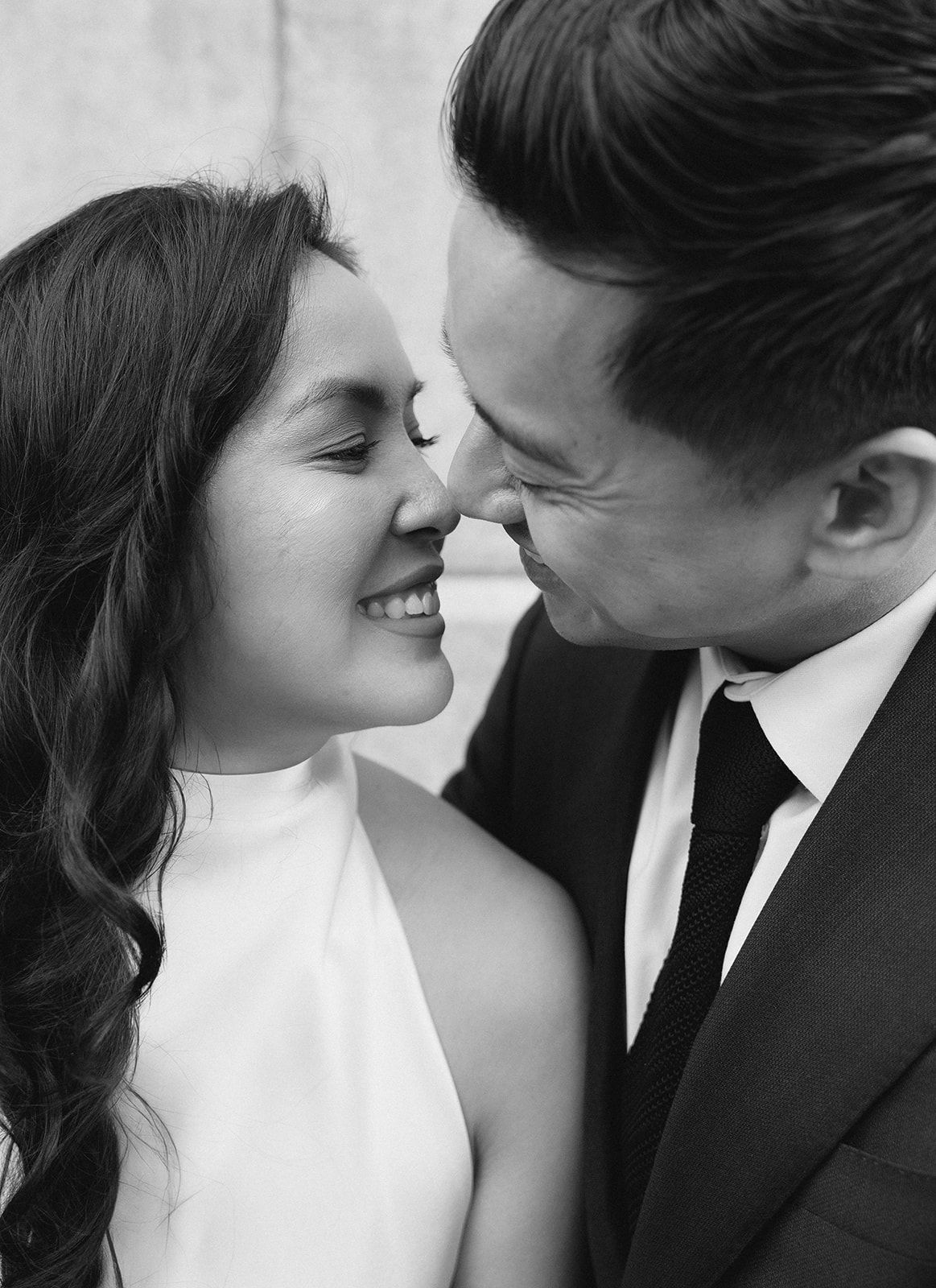 A black and white close-up of a smiling bride and groom sharing an intimate romantic moment.