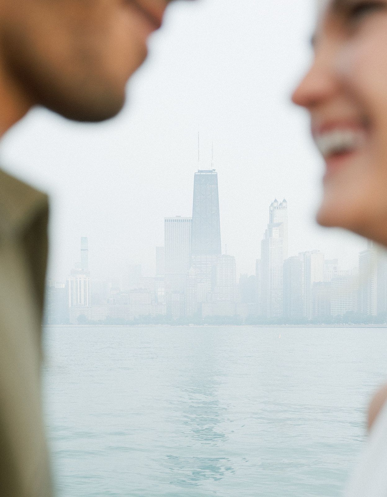 Romantic couple framed against the misty Chicago skyline and Lake Michigan waterfront view.