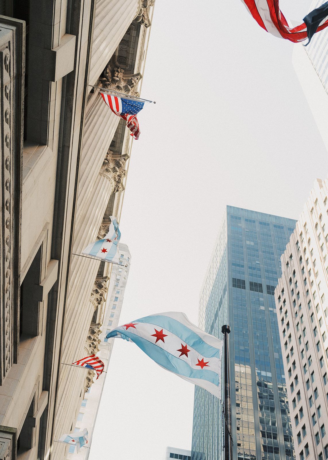 Chicago city flags and American flags waving between skyscrapers in downtown Chicago, Illinois.