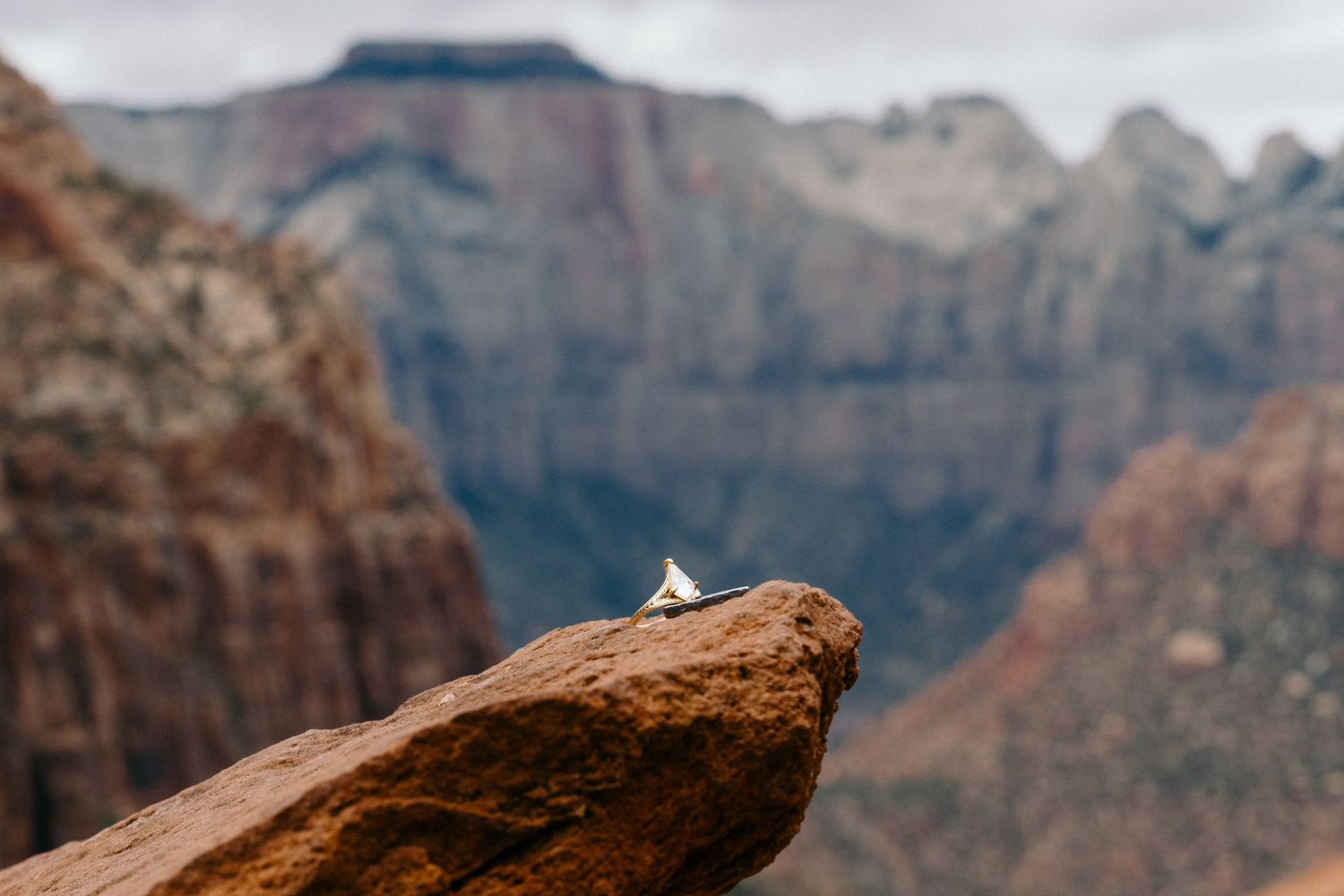 A small white tent perched on a red rock ledge with stunning Zion Canyon mountain views in the background.