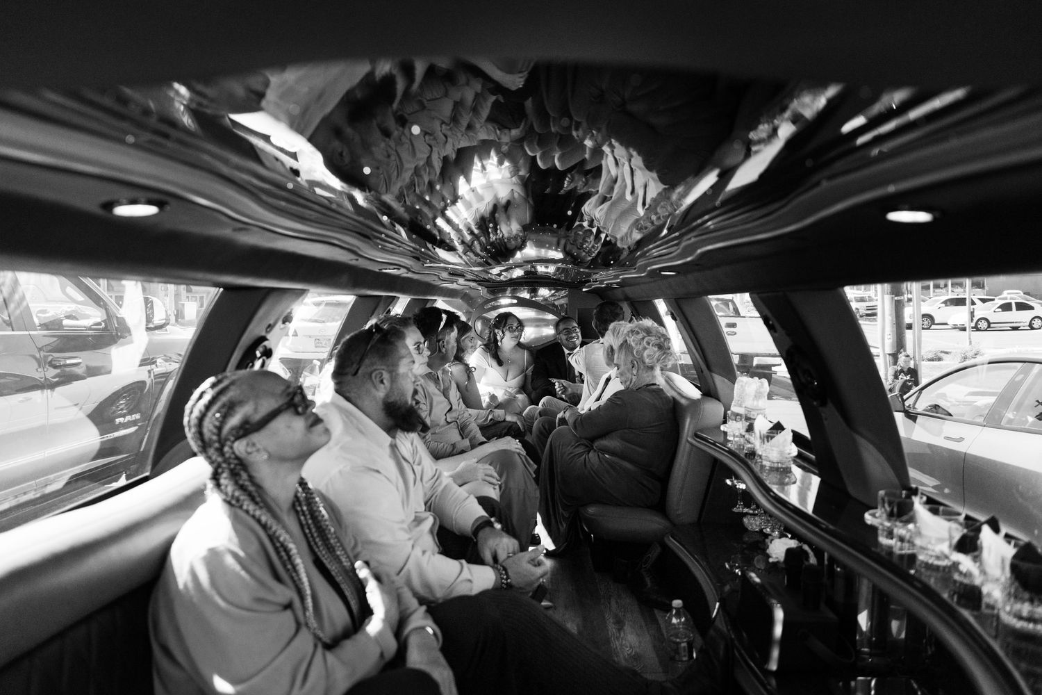 Black and white photo of a group of guests celebrating inside a decorated stretch limousine.
