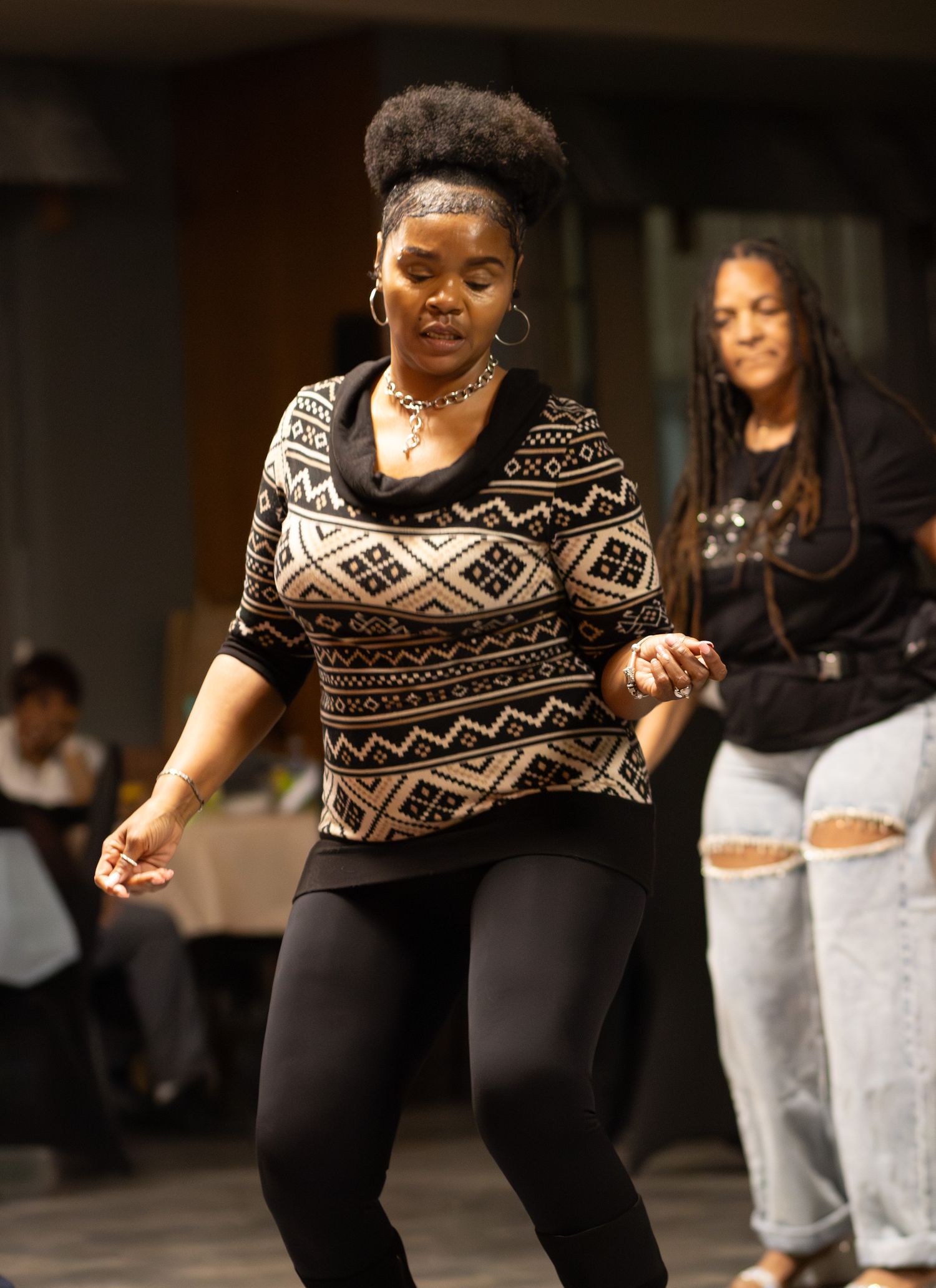 A candid shot of a woman dancing at an indoor social gathering, captured by a professional photographer.