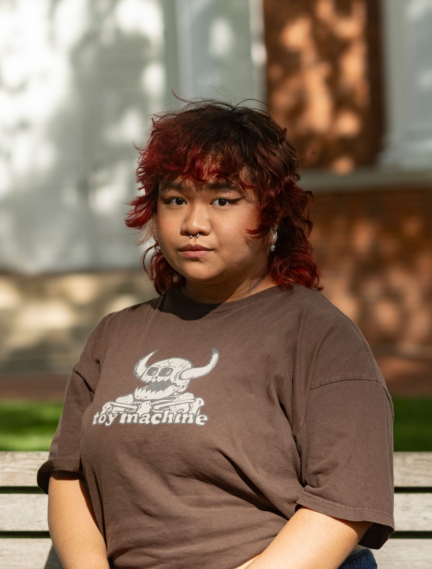 A casual outdoor headshot of a person sitting on a bench, captured by a professional portrait photographer.