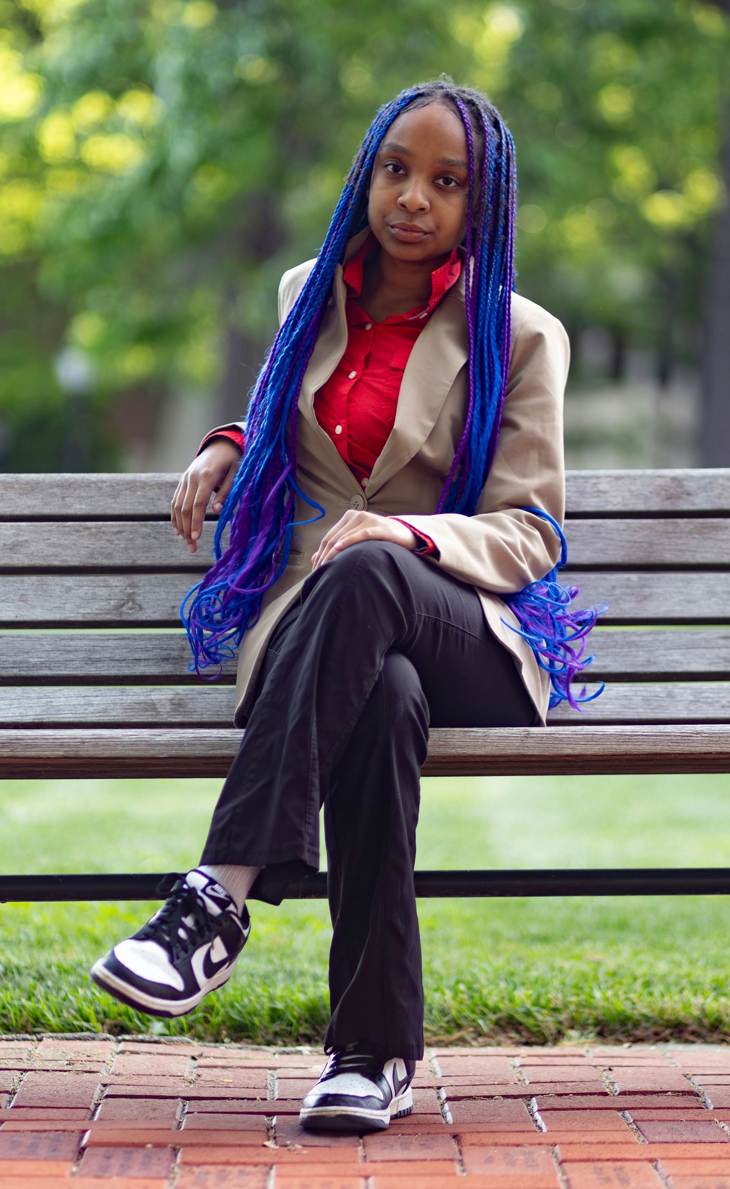 A stylish, natural light portrait of a woman in a blazer sitting on a bench outdoors, captured by a professional portrait photographer.