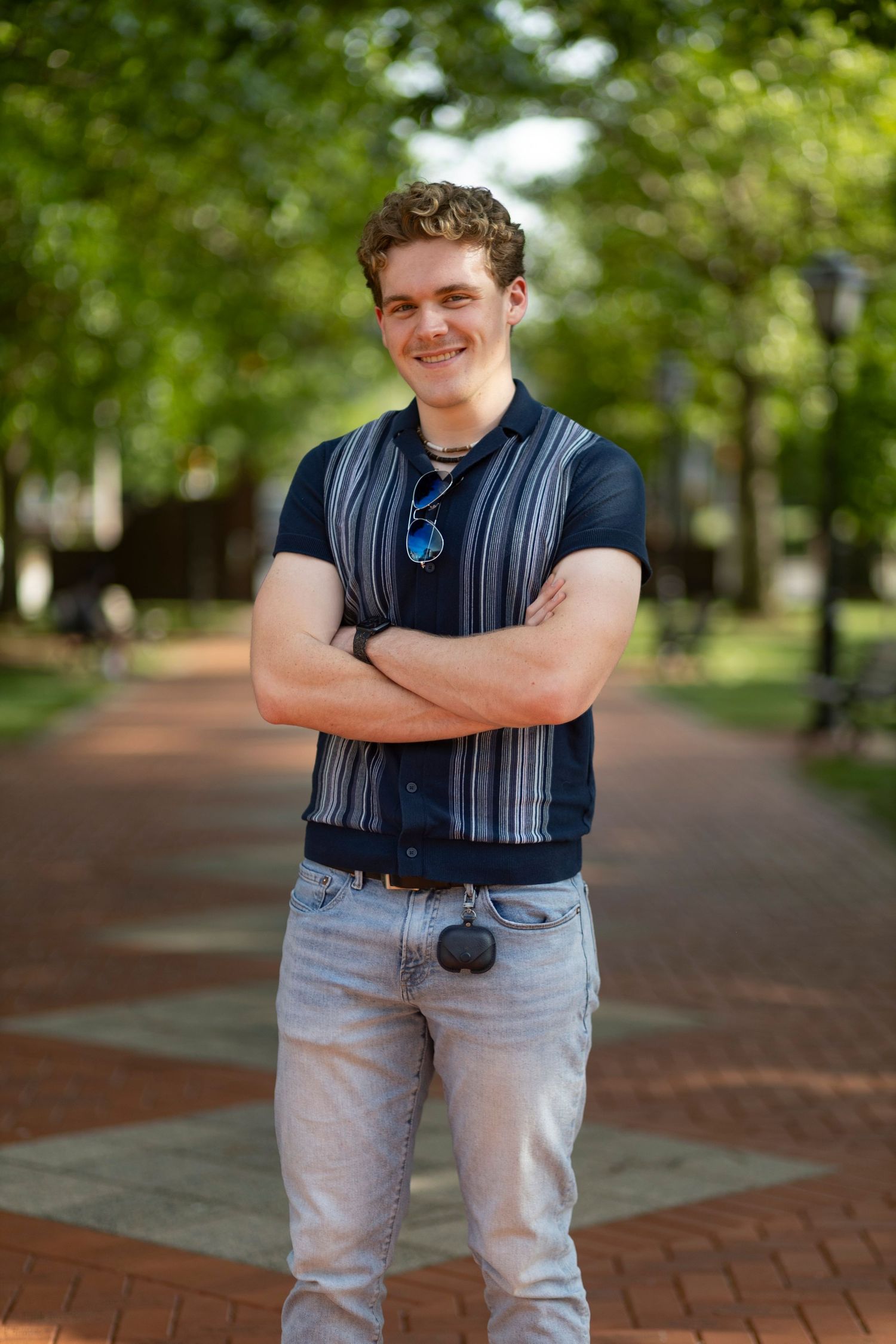 A confident, natural light portrait of a smiling man outdoors on a brick path, captured by a professional portrait photographer.