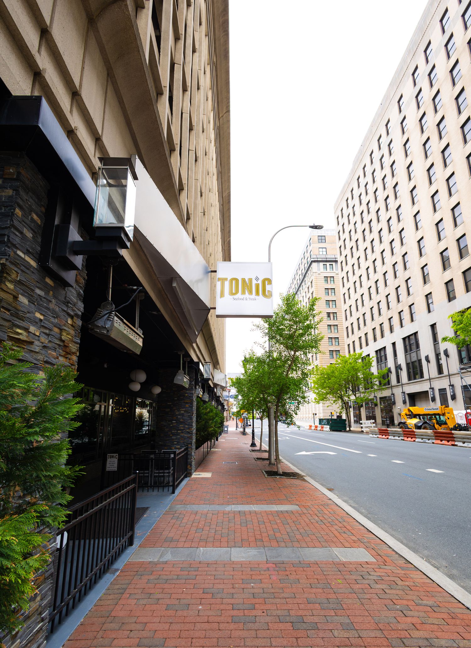 A wide architectural perspective of a city sidewalk next to a building with Tonic signage, captured by a professional landscape photographer