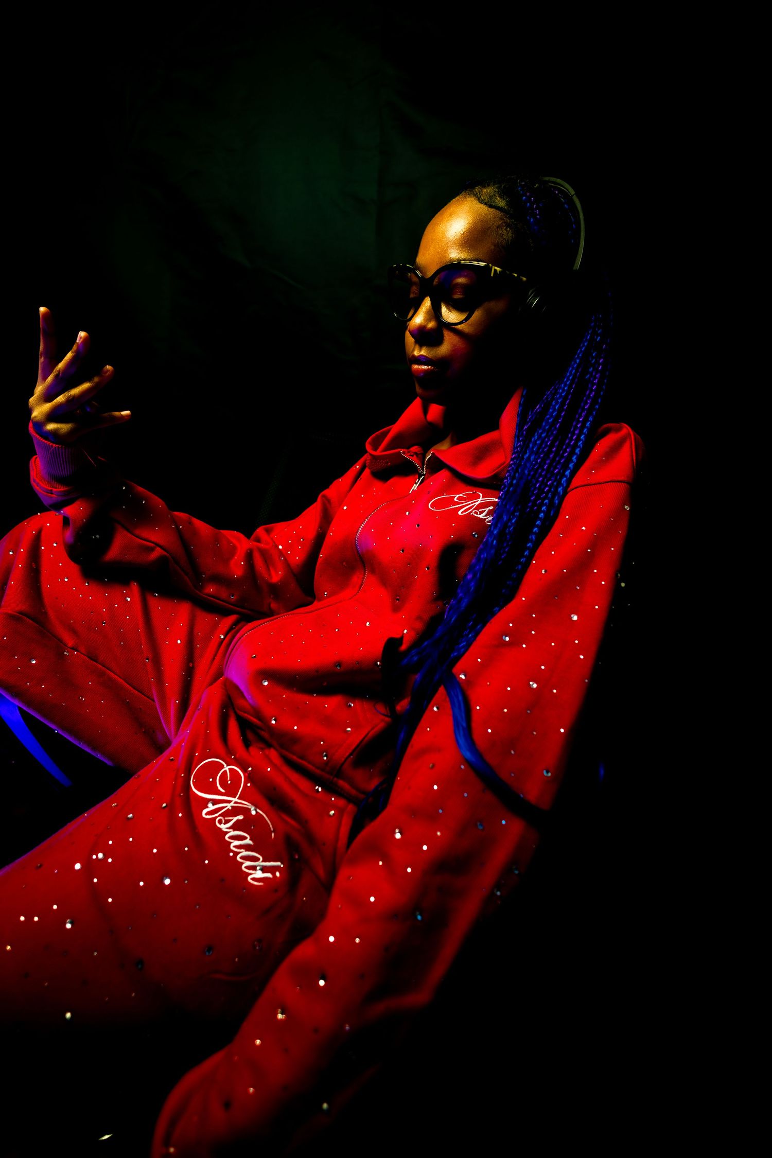 A moody, high-contrast portrait of a woman in a red tracksuit under dramatic studio lighting, captured by a professional creative photograph