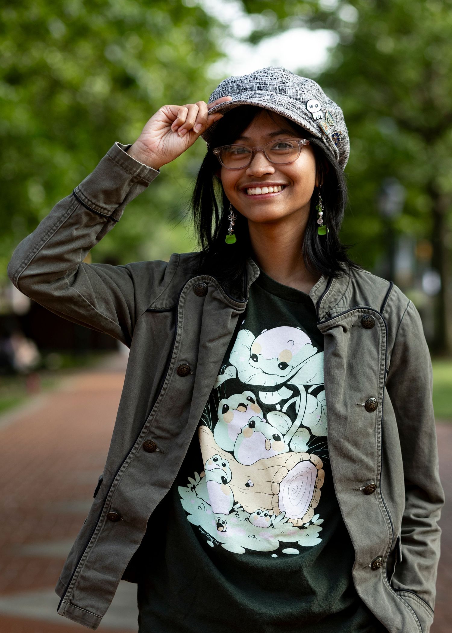 A casual natural light portrait of a smiling woman in a cap and jacket outdoors, captured by a professional portrait photographer.