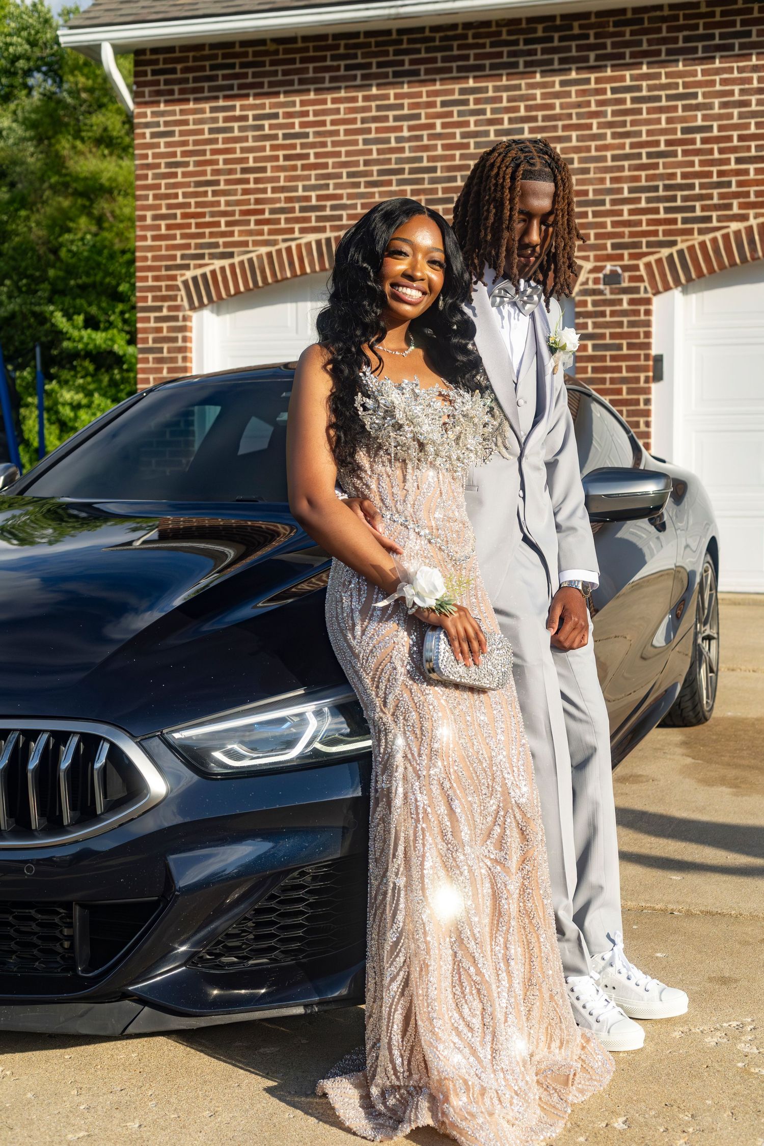 Professional outdoor prom photoshoot featuring a couple in formal wear with a luxury vehicle, perfect for a portrait.