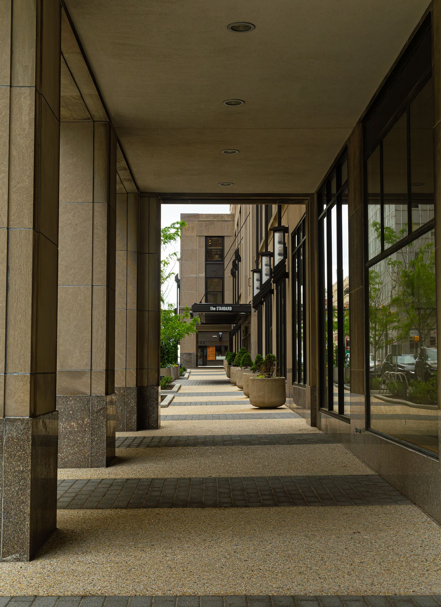 An architectural perspective down a covered stone walkway next to storefront windows, captured by a professional landscape photographer.