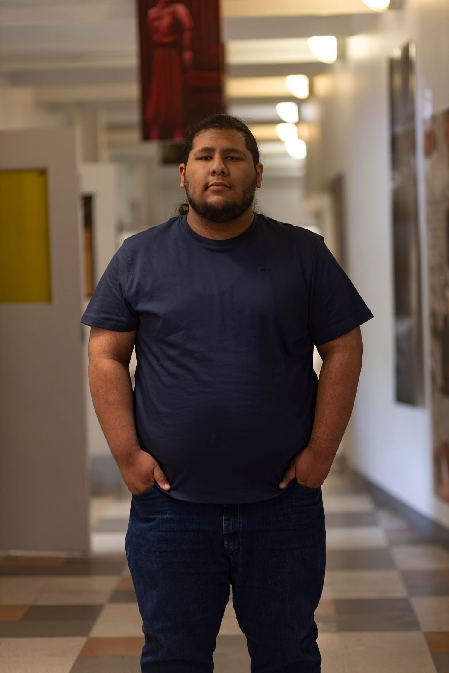 A casual studio-style portrait of a man standing in a hallway, captured by a professional portrait photographer.