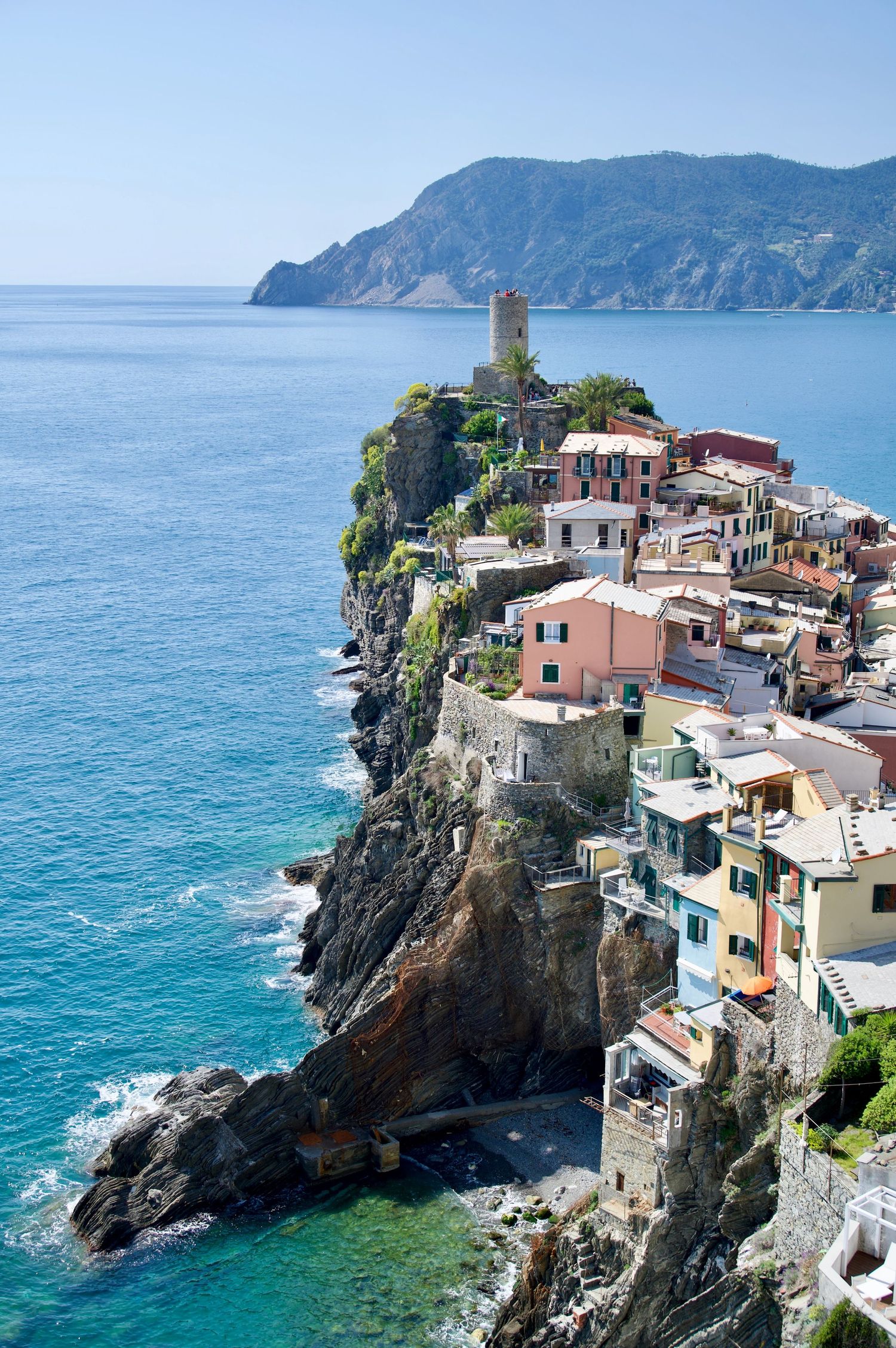 A view of Vernazza in the Cinq Terres taken from the coastal hiking path looking at the colourful buildings and the dramatic cliffs
