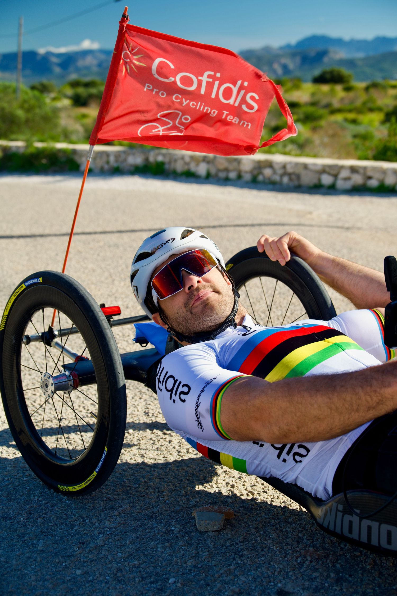 Mathieu Bosredon, Team Cofidis paracyclist at the summit of the Montgo hill,  with a Team Cofidis flag.