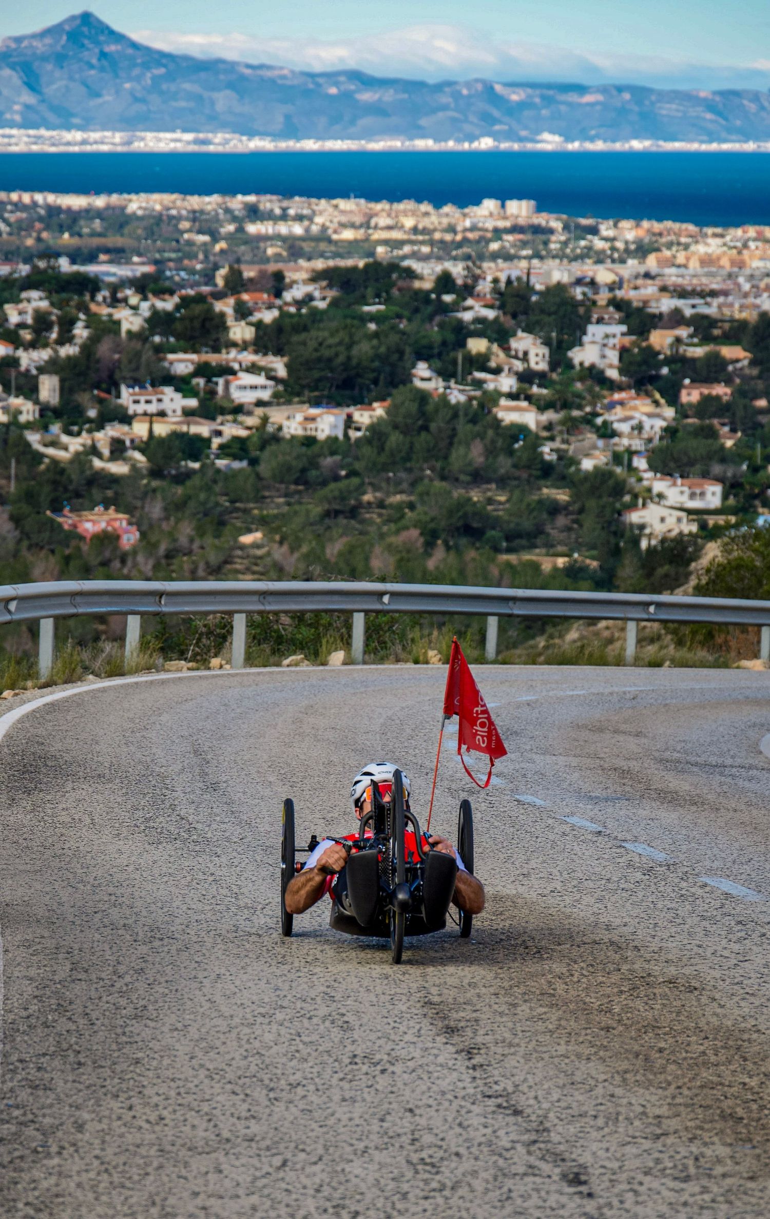 Mathieu Bosredon of Team Cofidis in his handbike climbing the Montgo climb with Denia in the background.