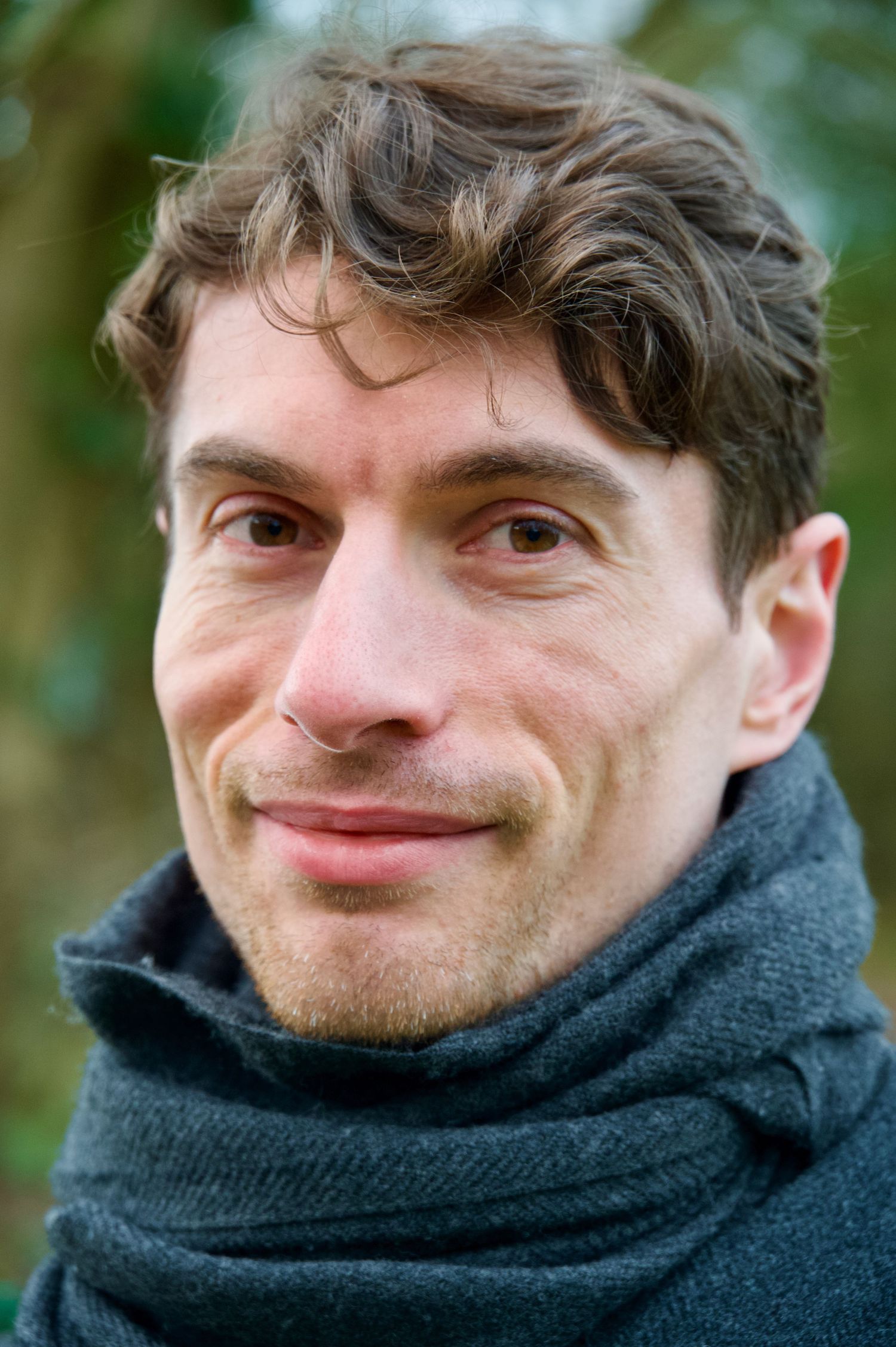 A close up portrait of a man wearing a scarf.