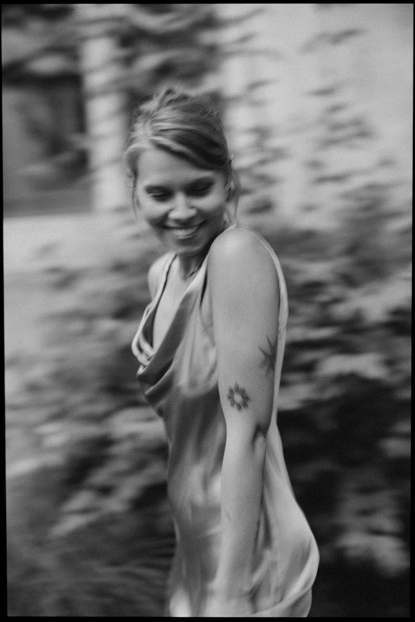 Black and white photo of a woman in flowing dress smiling while spinning in motion.