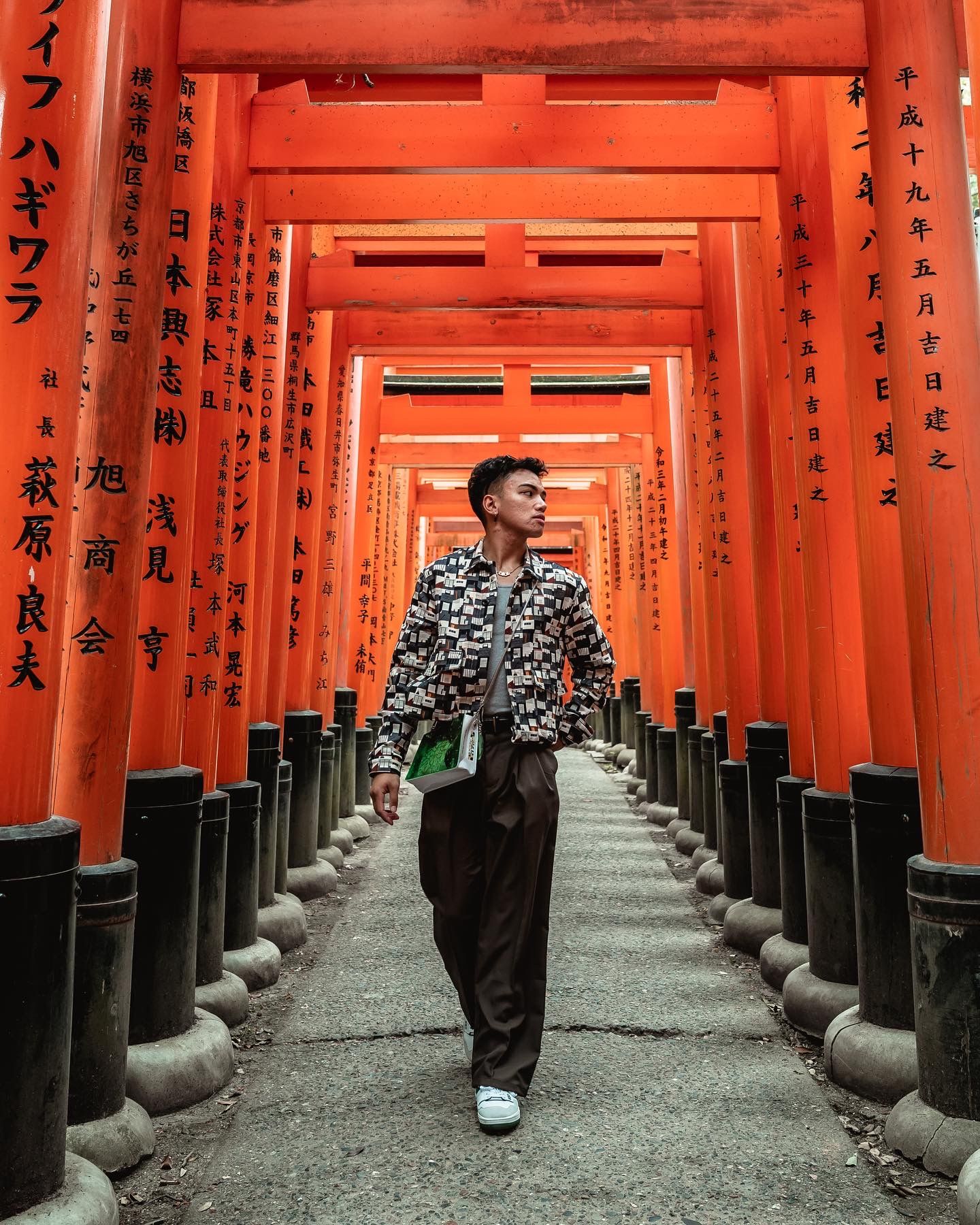 A traveler walks through vibrant red torii gates at Fushimi Inari Shrine in Kyoto.