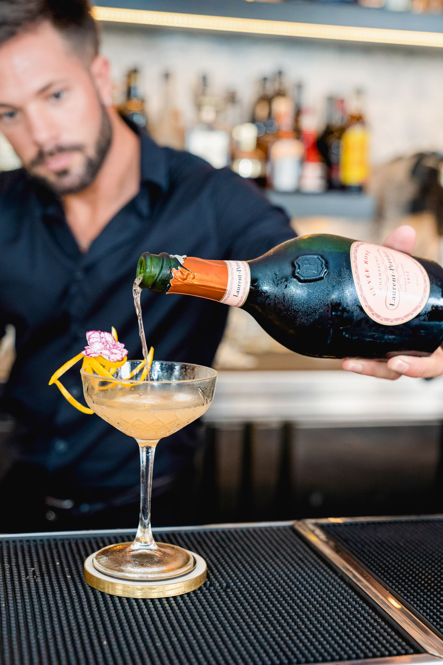 Bartender preparing cocktails behind the bar in a Málaga restaurant, captured with natural movement, warm light and an authentic lifestyle a