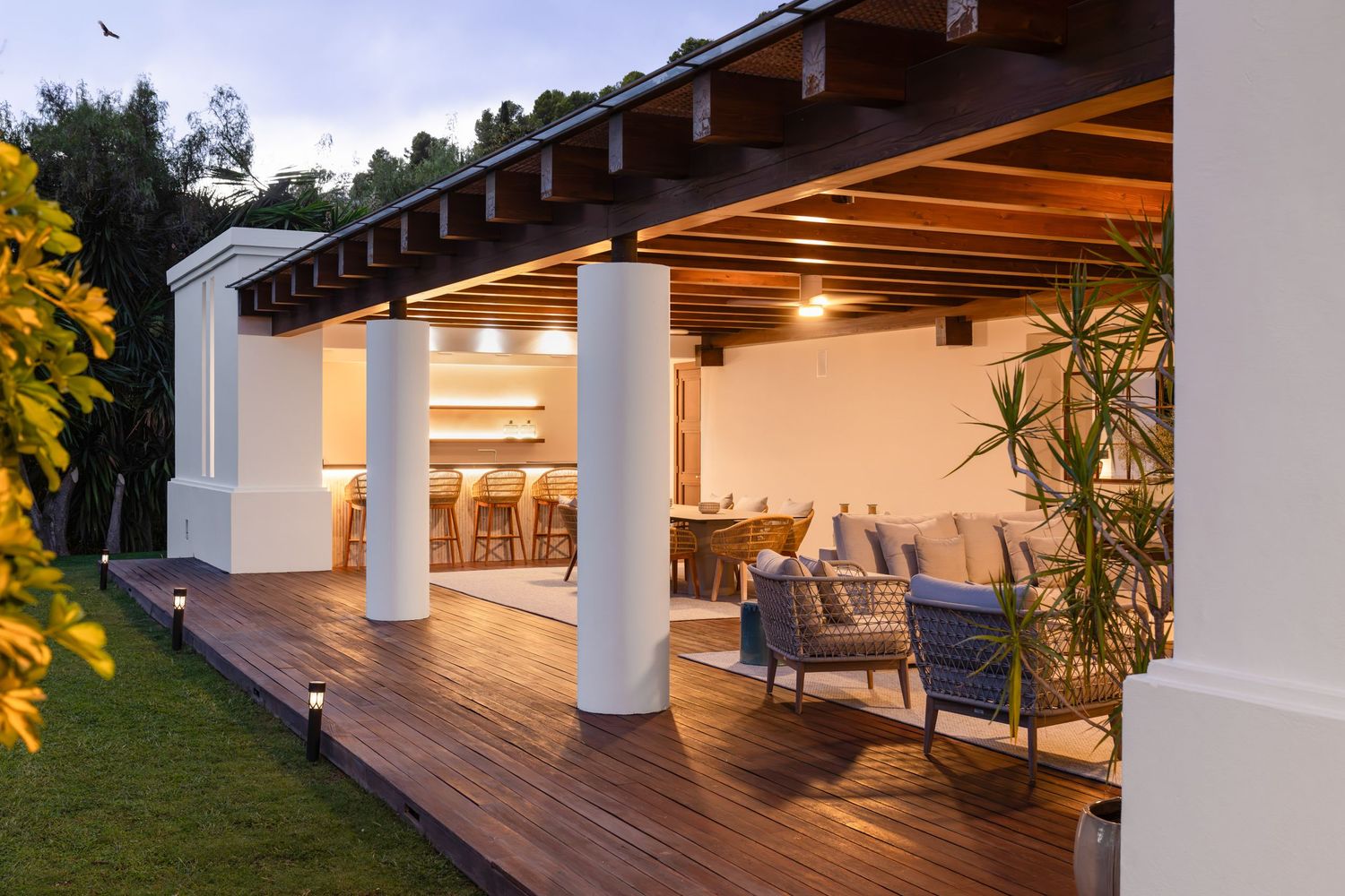 Luxury villa photographed at dusk in Málaga, with warm interior lighting and soft evening tones highlighting architecture and outdoor spaces
